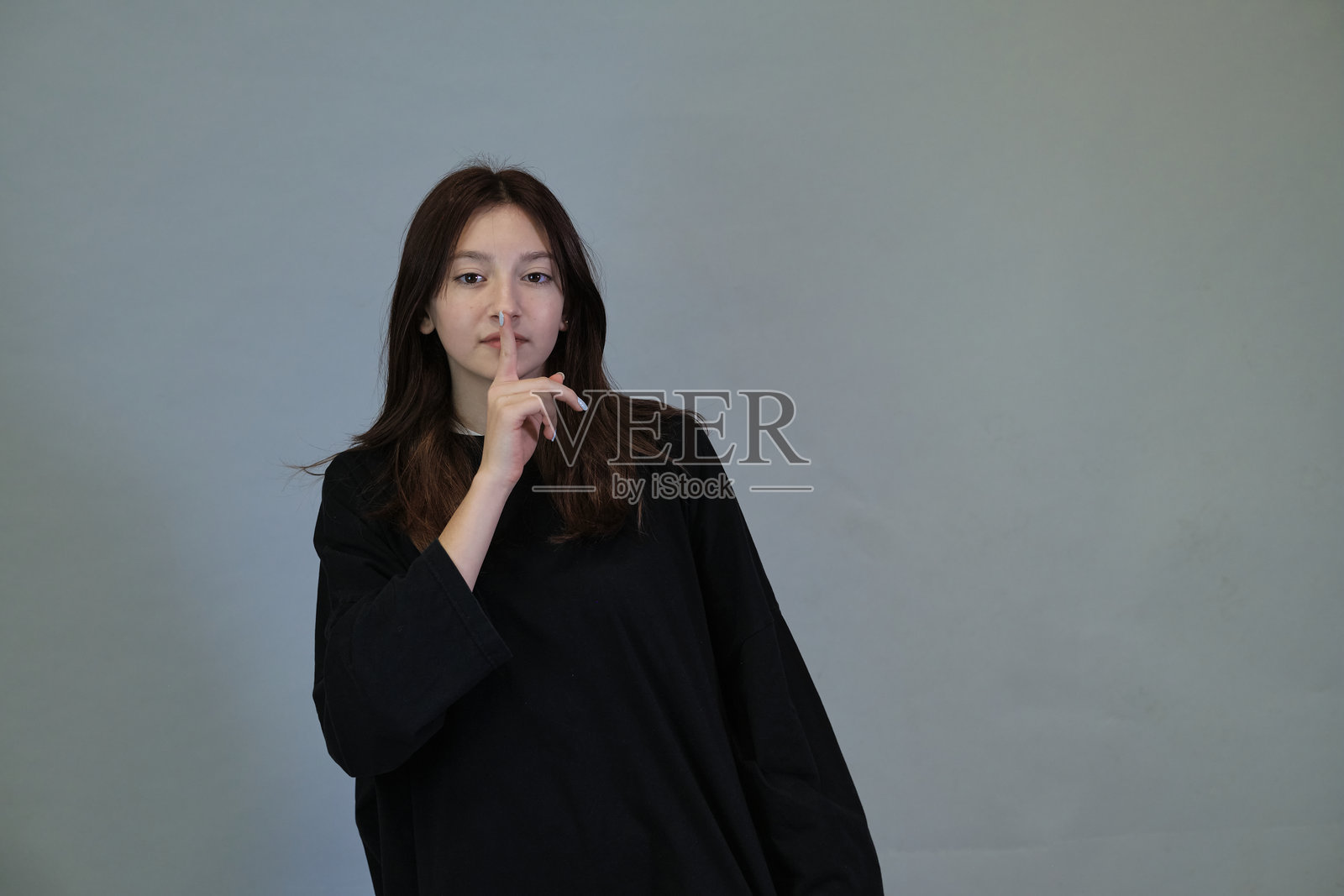 年轻女性以无声的手势表达，在喧嚣的世界中呼应对宁静的需求。捕捉到一刻的静谧。照片摄影图片