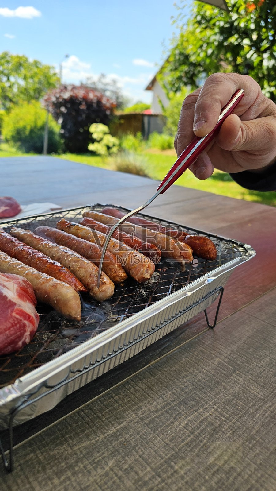 一次性烧烤架放在户外的桌子上，处于野餐模式。照片摄影图片