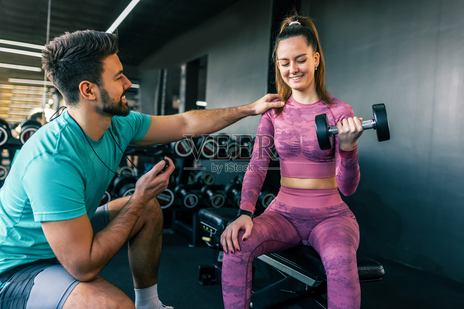 男子在健身房帮助女子举重照片摄影图片