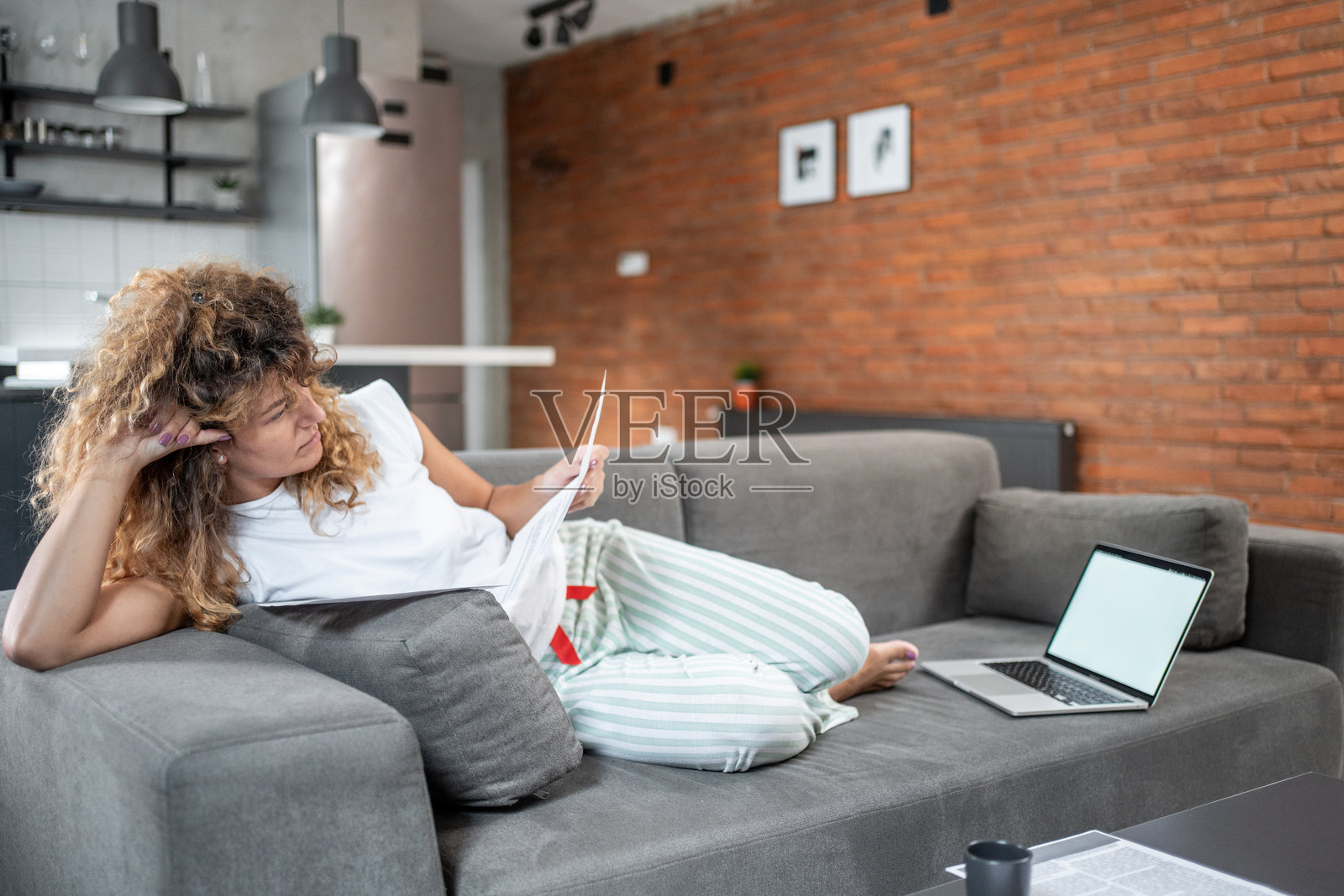 女人躺在沙发上在家中办公室阅读文件照片摄影图片