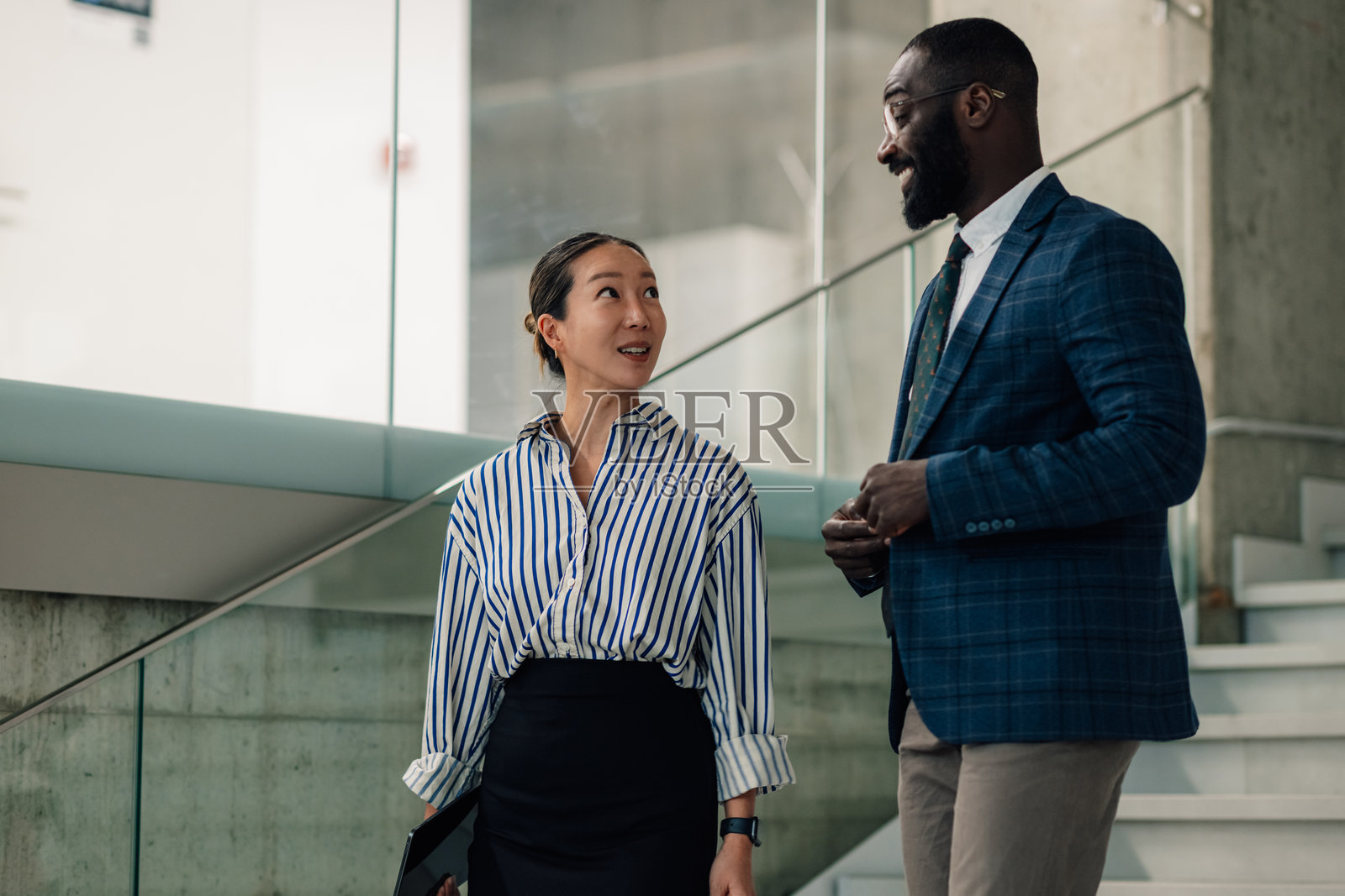 商务人士在办公大楼内边走边谈照片摄影图片