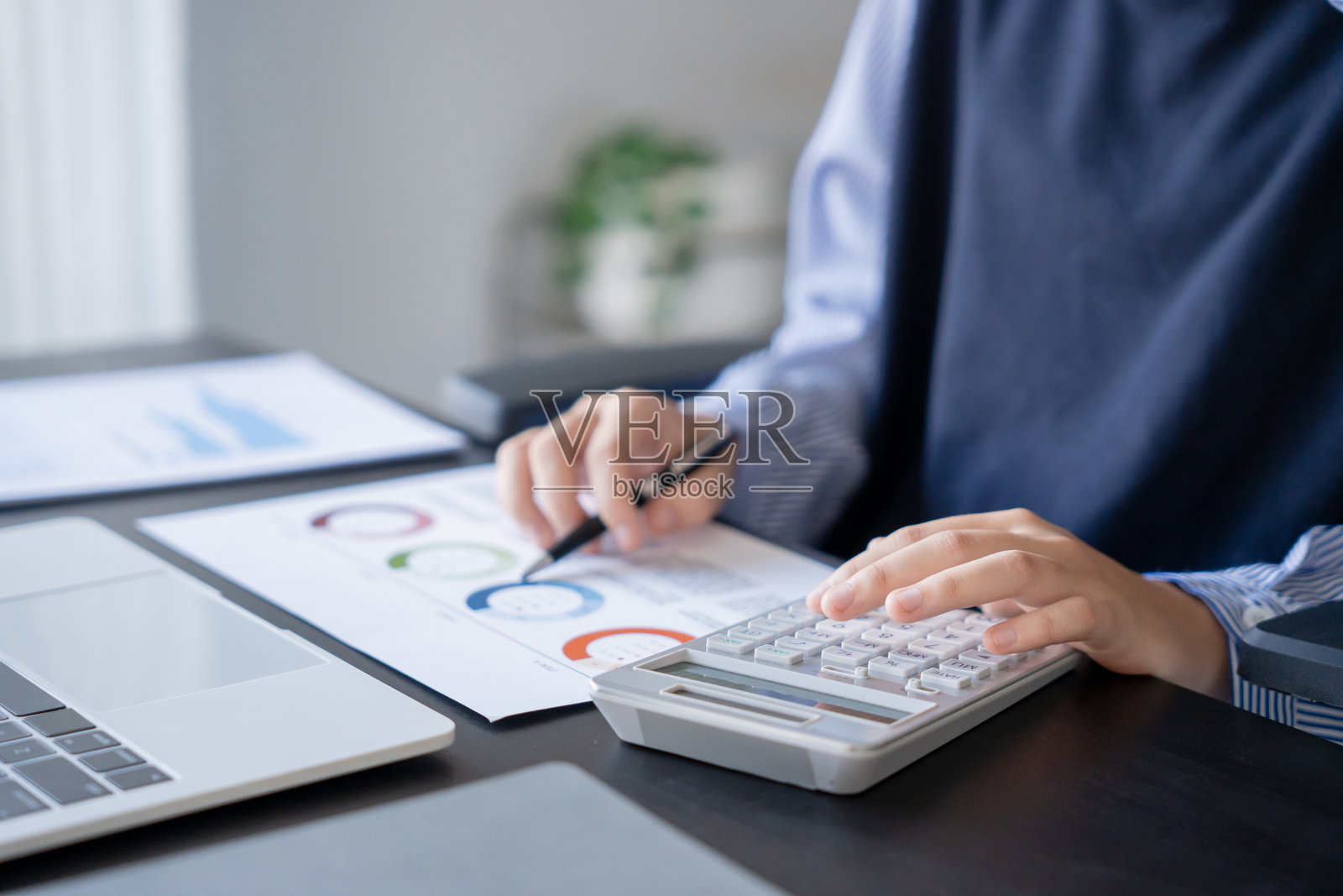 亚洲女商人在用笔、笔记本电脑和计算器处理文件照片摄影图片