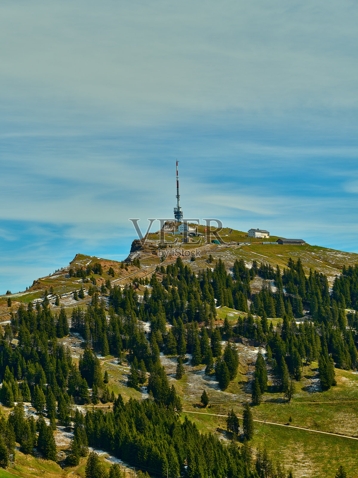 山顶风景有一座通信塔，四周环绕着郁郁葱葱的森林，天空晴朗。照片摄影图片