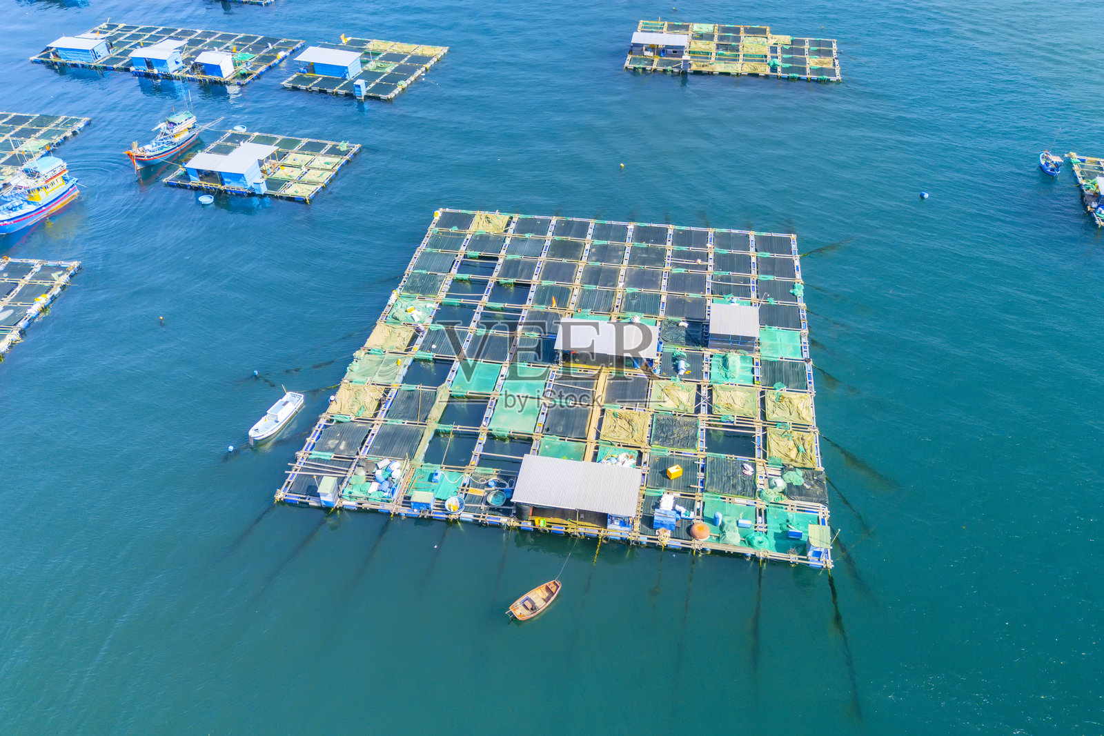 热带岛屿上渔村的空中俯视图，展示了用于养殖海洋动物的水产养殖笼结构。照片摄影图片