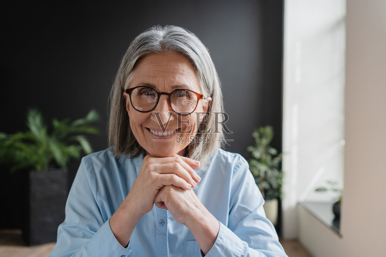 快乐的中年女性职业经理人，微笑的成熟执行官，60岁女性企业家，自信的商界女性，佩戴眼镜在办公室内。头像肖像。照片摄影图片