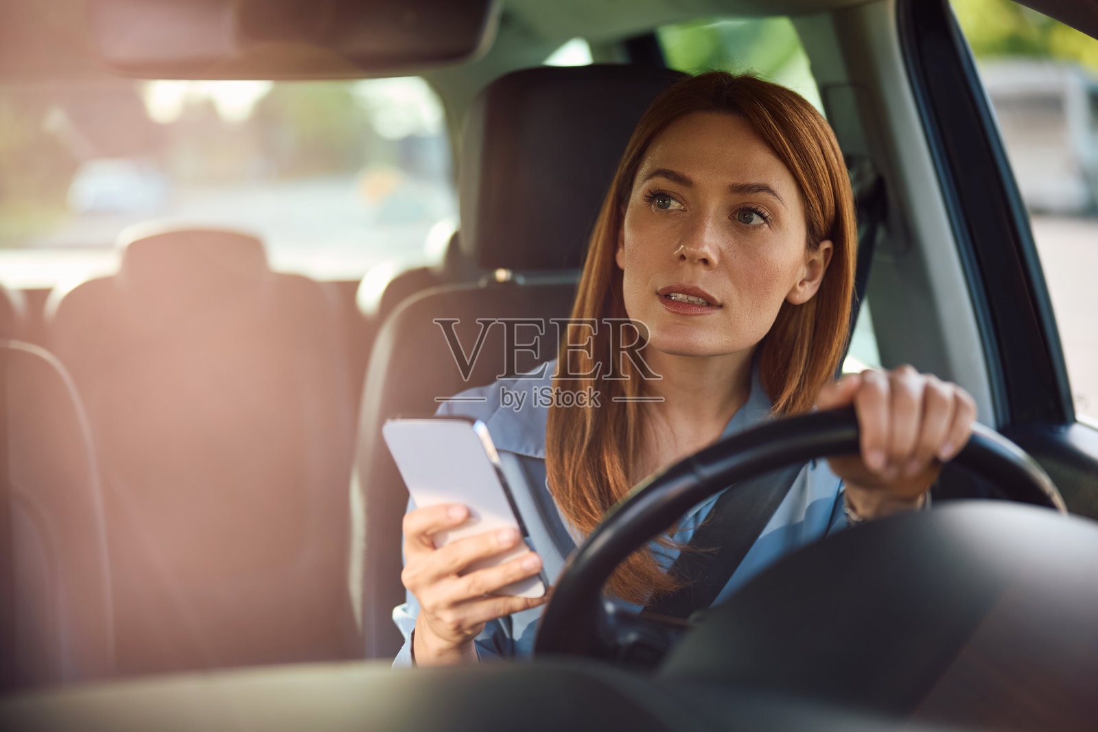 不确定的女性在开车时使用手机，寻找转弯的方向。照片摄影图片