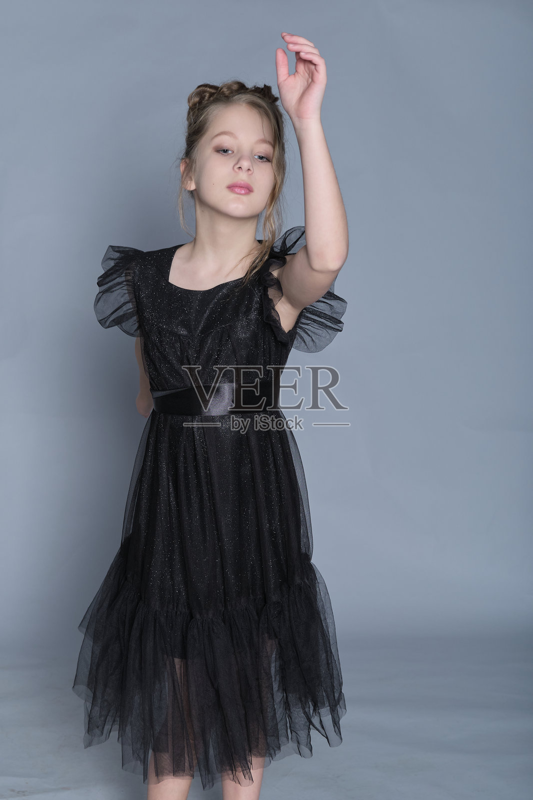 一位穿着黑色荷叶边裙子的年轻舞者优雅地伸展手臂，展现出优雅与灵动。这张图片展示了儿童舞蹈的美，融合了舞动与高端时尚，呈现出一种精致的外观。照片摄影图片