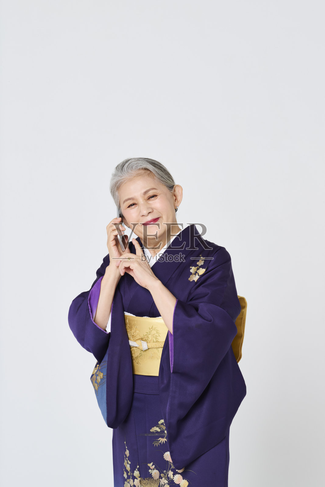 穿着紫色和服的老年女性正在使用智能手机照片摄影图片