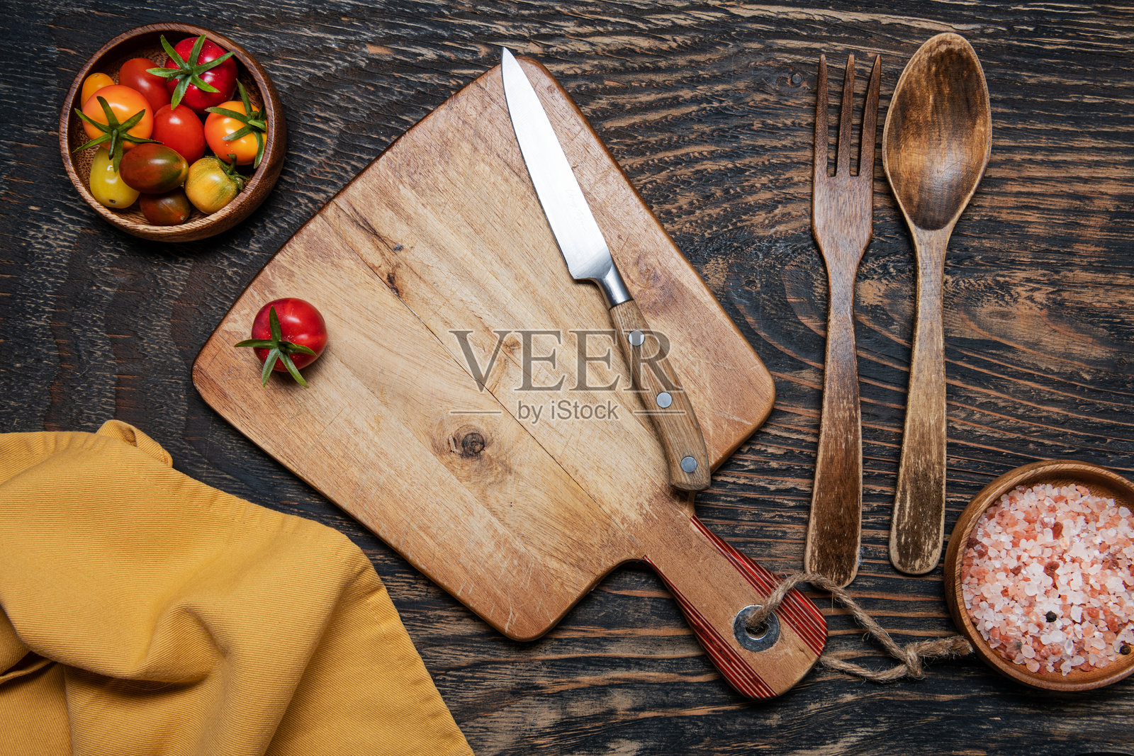 黑色木桌上的樱桃番茄、刀和切菜板。俯视图。留有文字空间。照片摄影图片