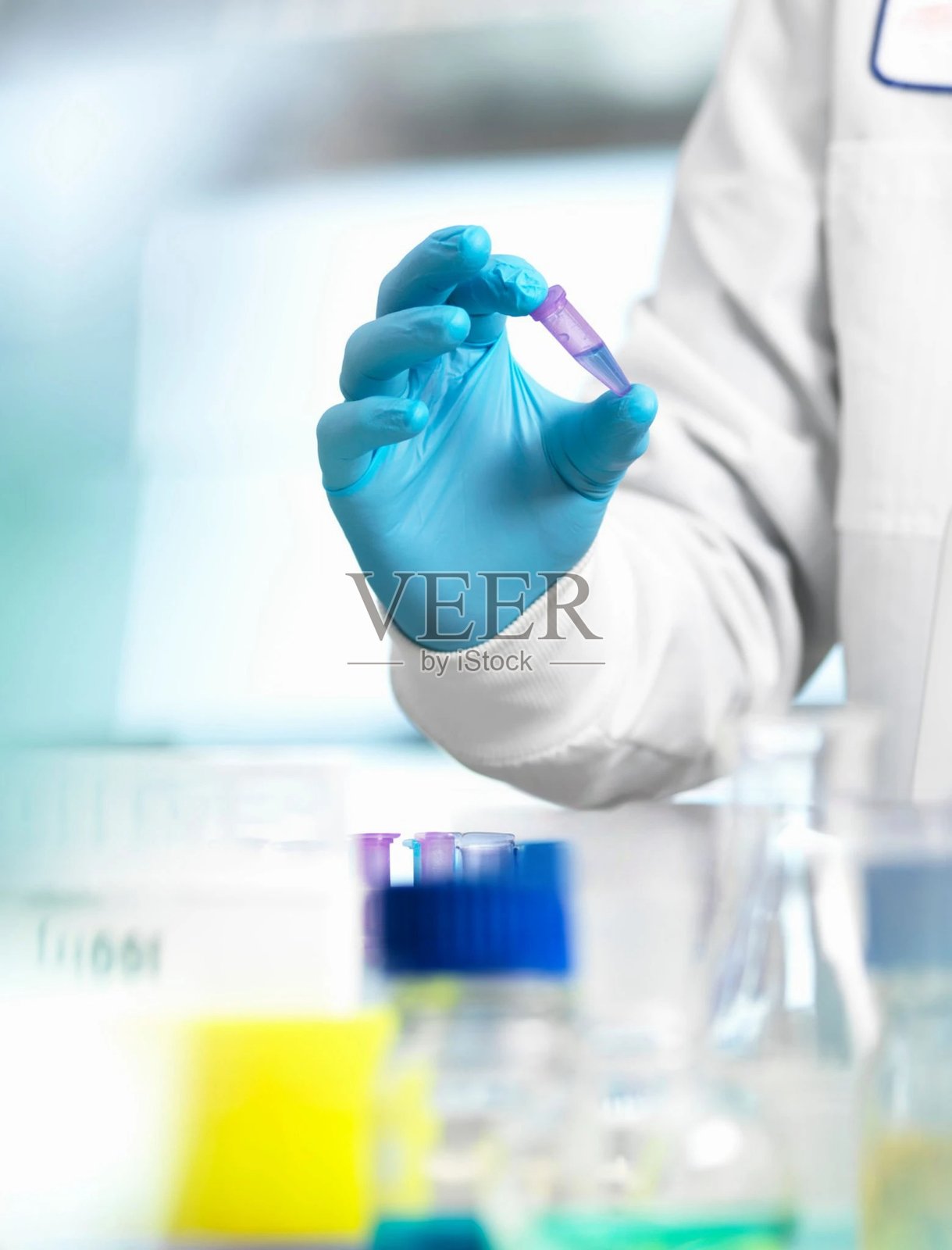 一位戴着手套的科学家在实验室中握着试管，进行科学研究和实验。照片摄影图片