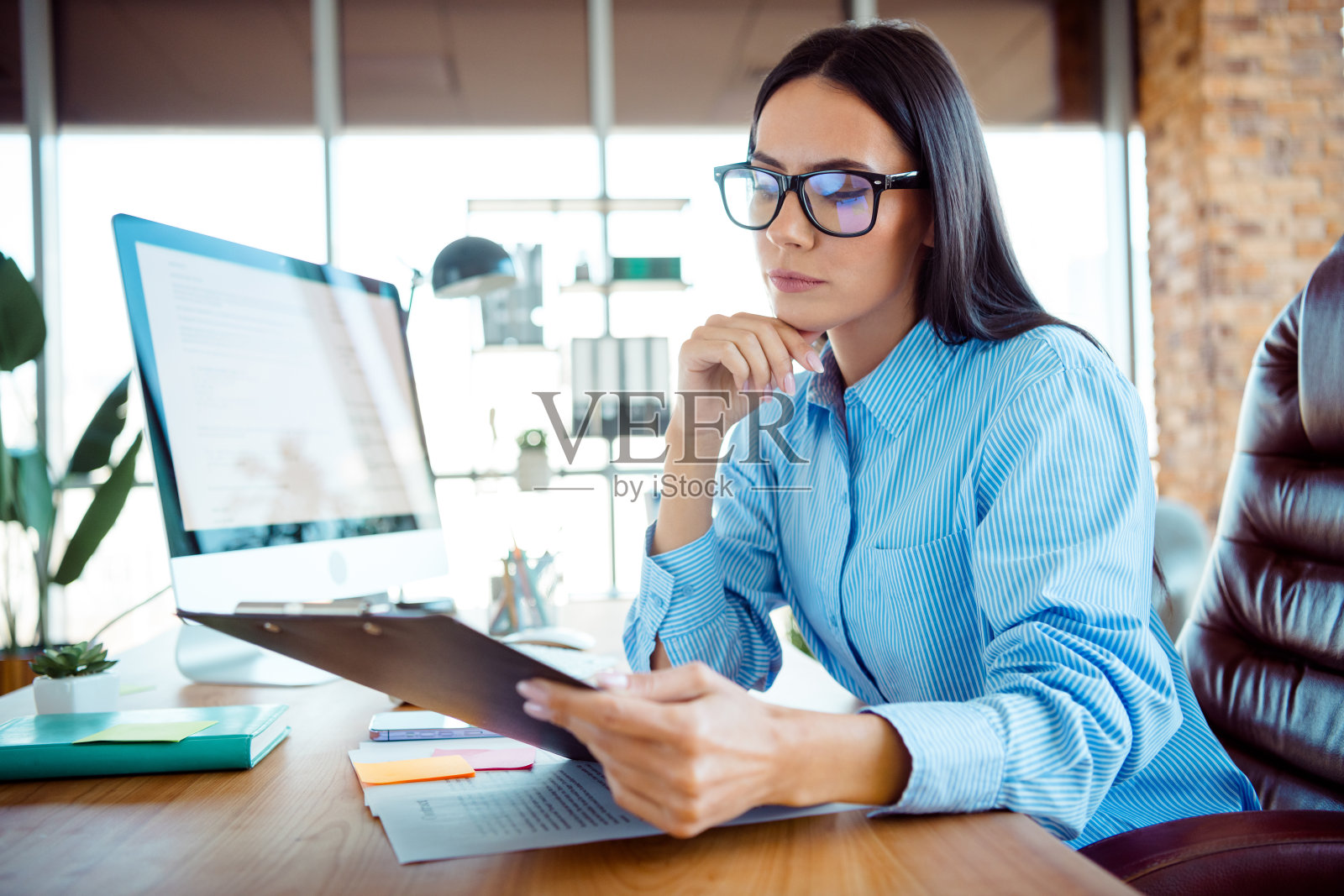 年轻职业女性在现代办公室专注于平板电脑和文件工作照片摄影图片