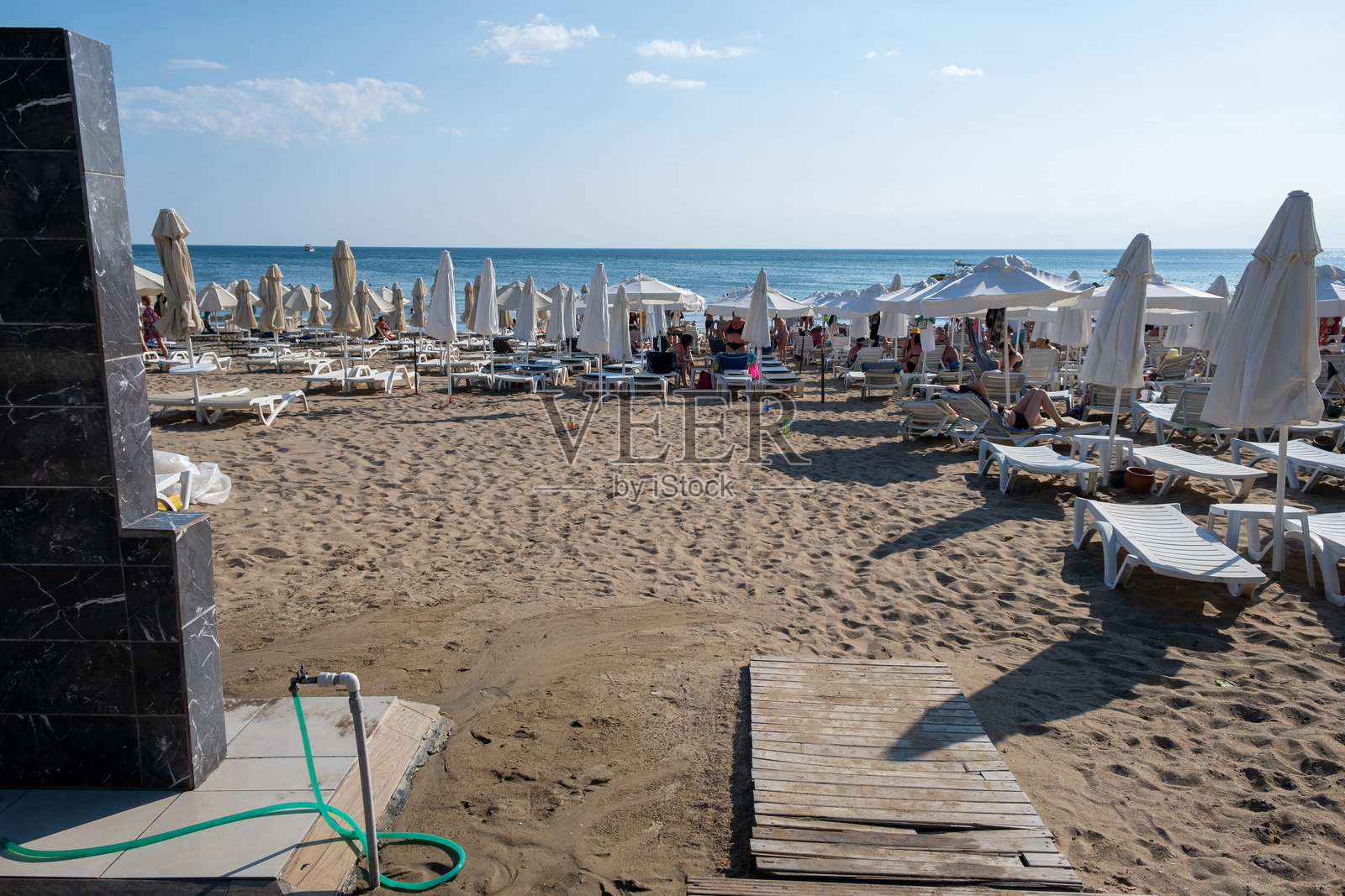 沙滩上有阳光躺椅和伞，人们在水边享受阳光明媚的一天照片摄影图片