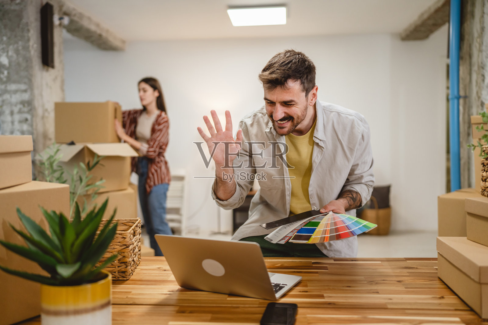 男子在视频通话中展示色彩调色板，女子则在旁边拆包。照片摄影图片