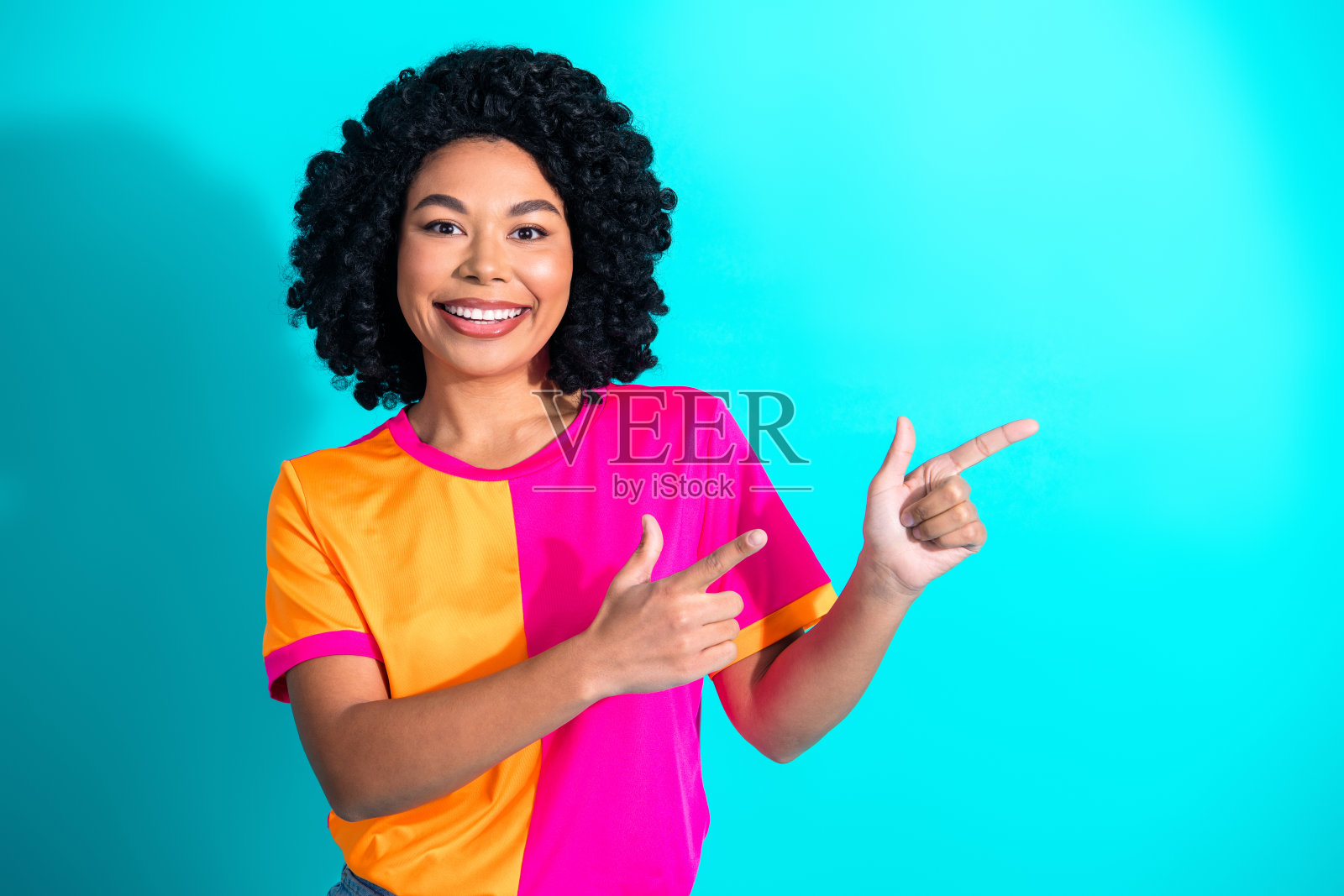 微笑的年轻女性，穿着活力四射的休闲风格，在青绿色背景下表现出兴奋的手势照片摄影图片