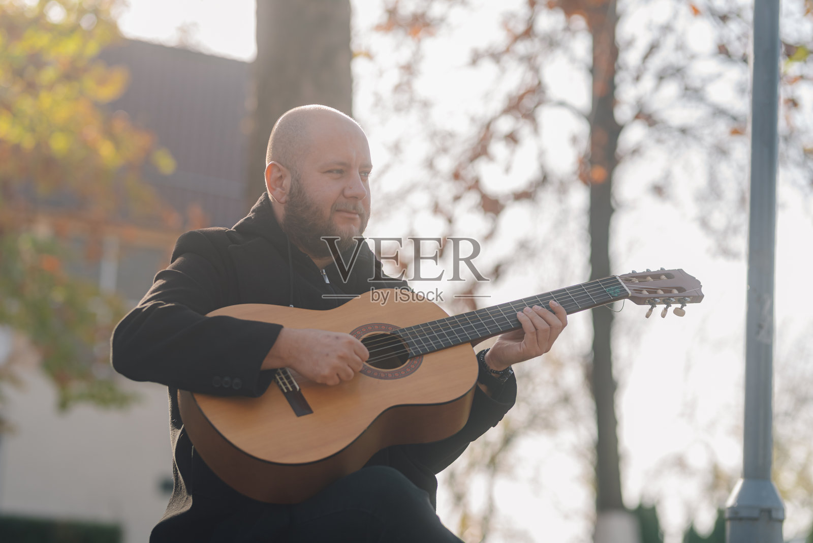 音乐家在秋日阳光下户外弹奏木吉他照片摄影图片