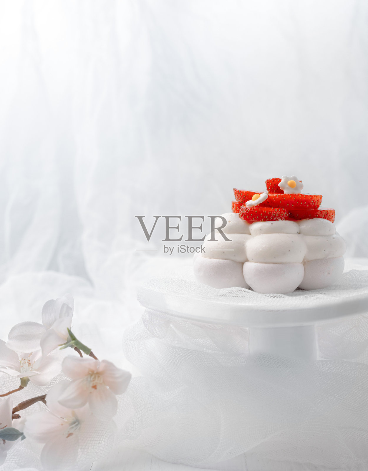 白色背景上，白色支架上的法式帕夫洛娃甜点，配有红色草莓。照片摄影图片
