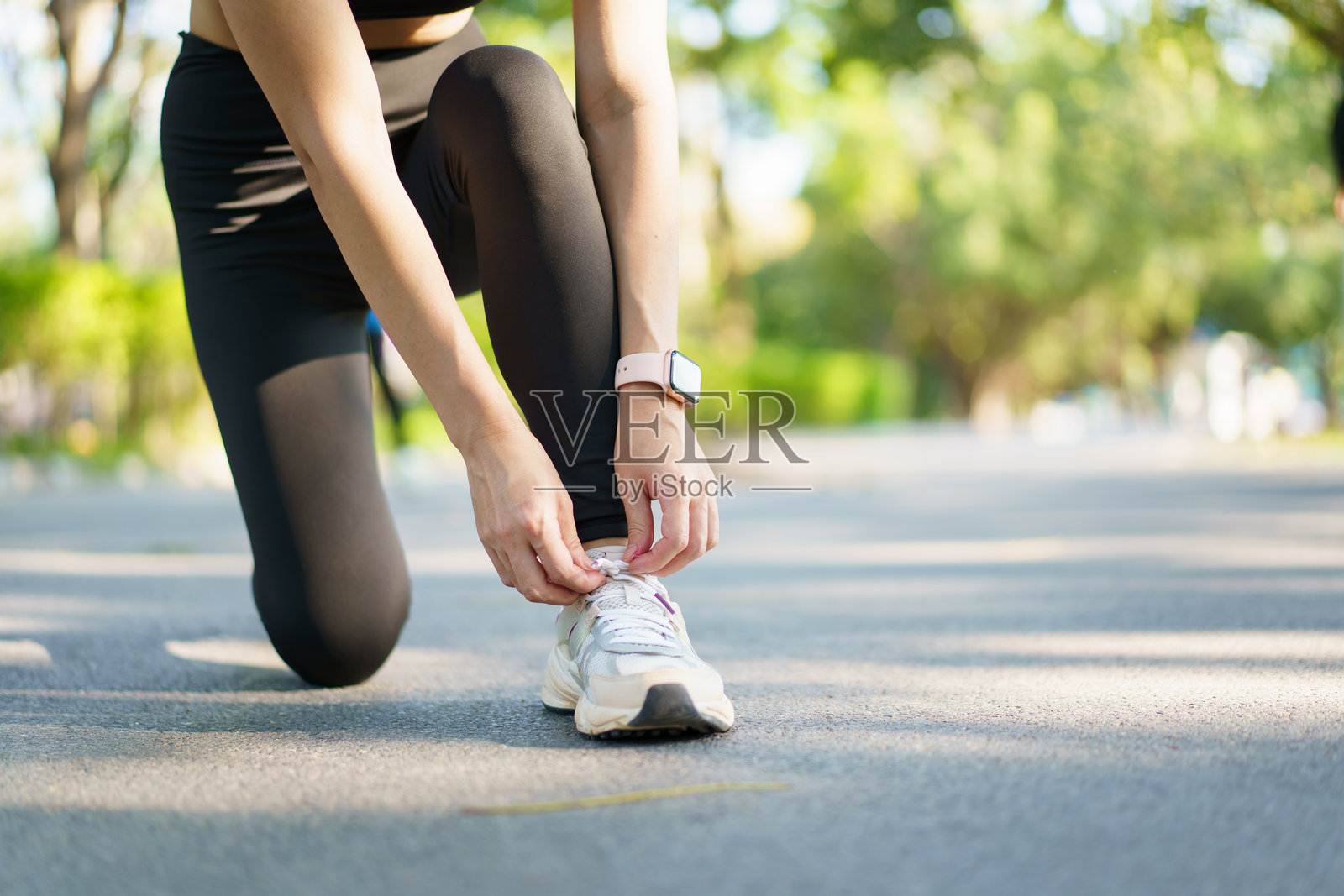 女人在公园跑步时系鞋带。照片摄影图片