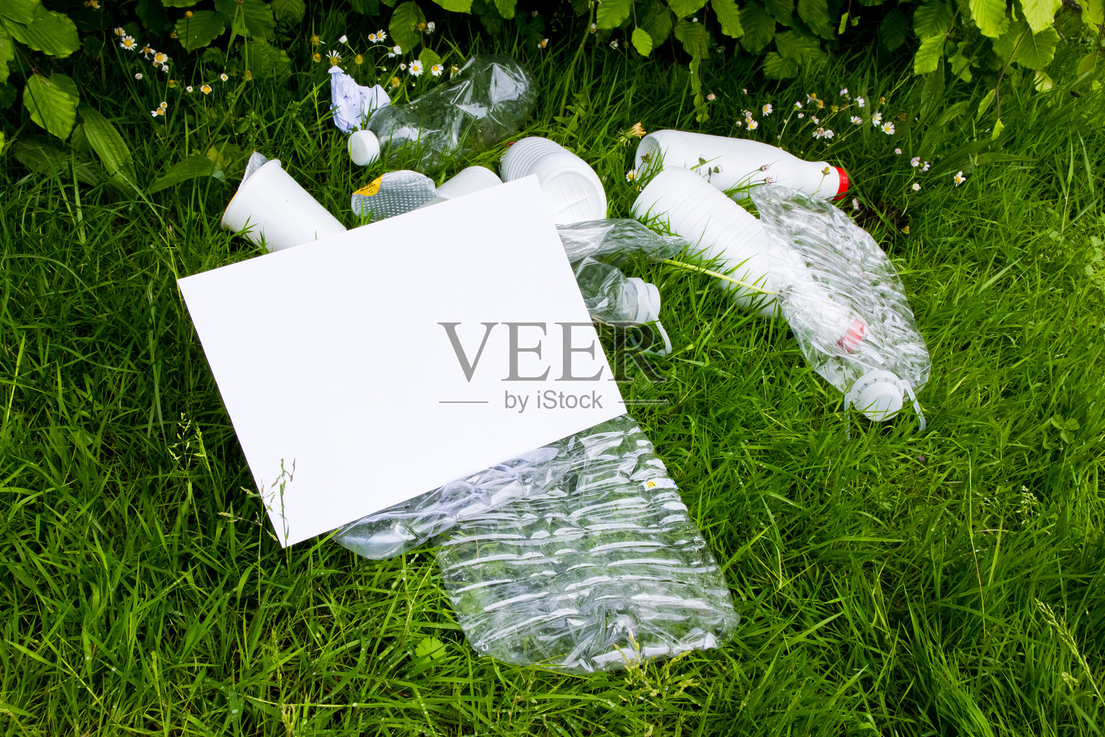 空白标志与草地上的塑料垃圾，突显环境问题照片摄影图片