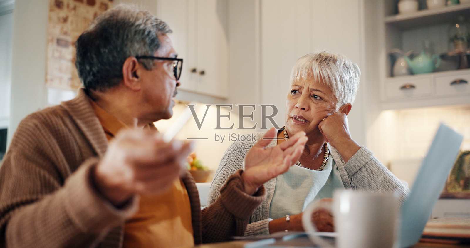 家中，老夫妻与笔记本电脑的问题，预算、金融危机及银行抵押贷款的讨论。老年人，男女双方就通货膨胀成本、债务告白和账单进行交谈。照片摄影图片