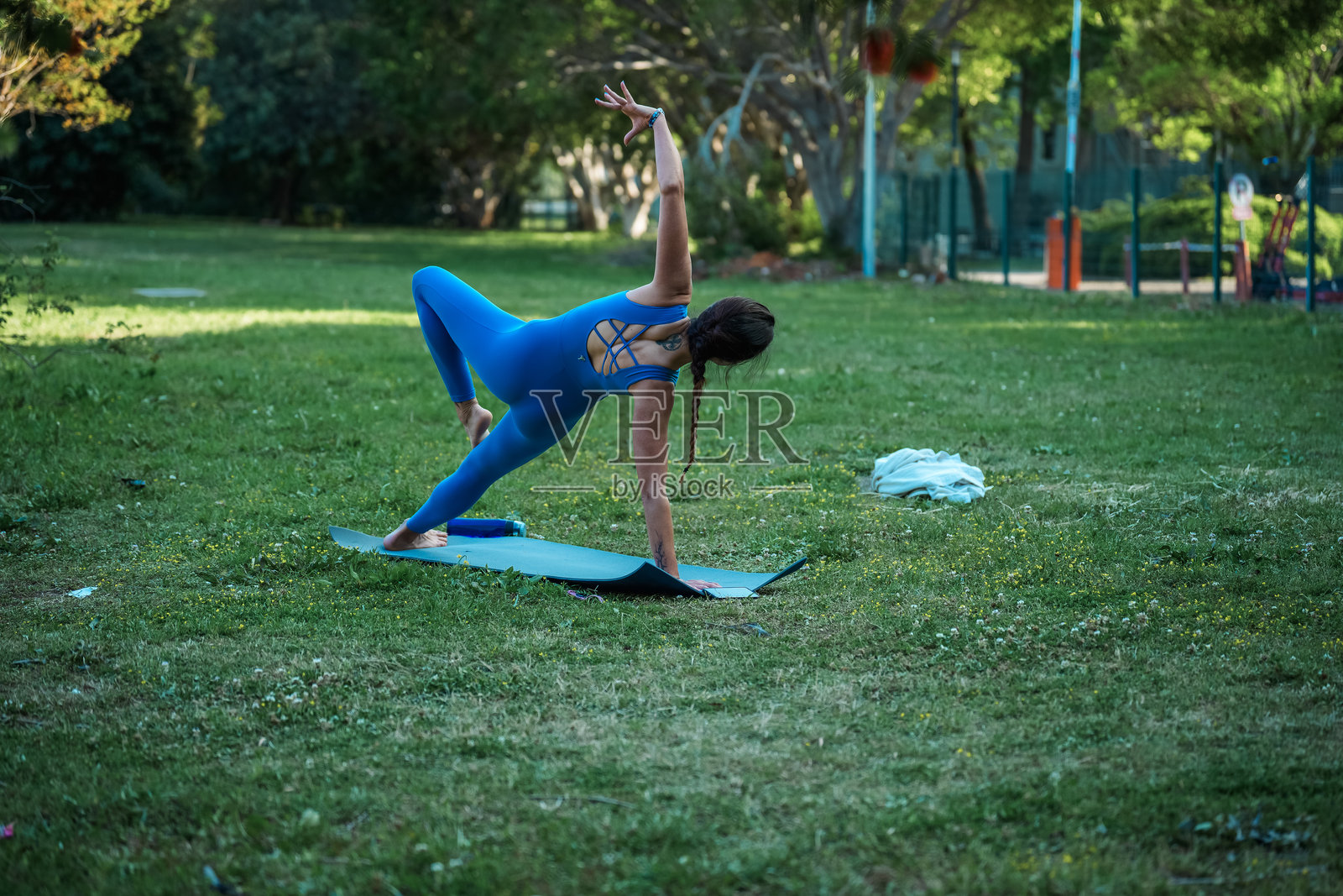 女性在公园的瑜伽垫上练习侧臂平衡姿势变体照片摄影图片