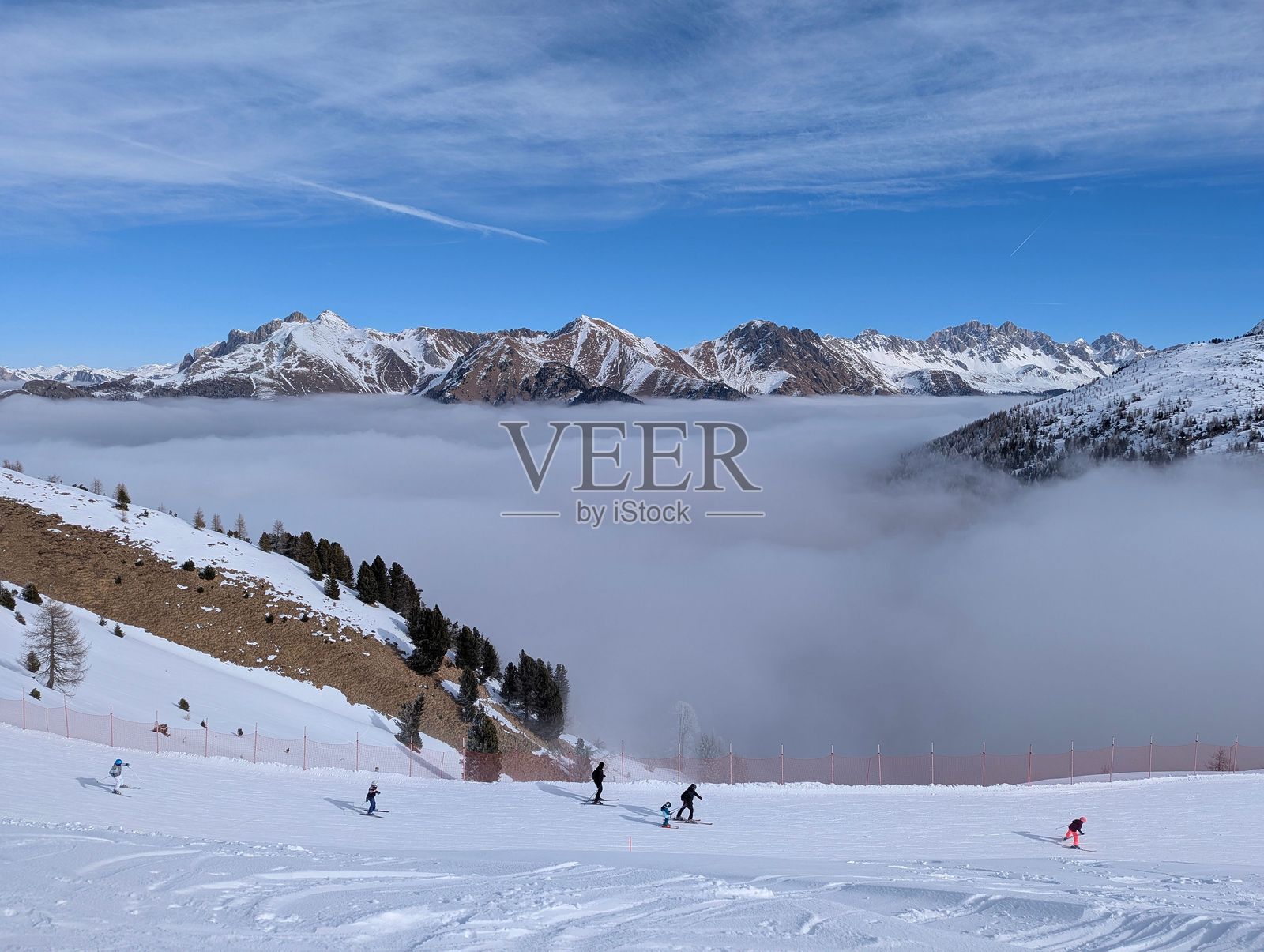 滑雪者在雪-covered斜坡上，远处是雾气缭绕的山景。照片摄影图片