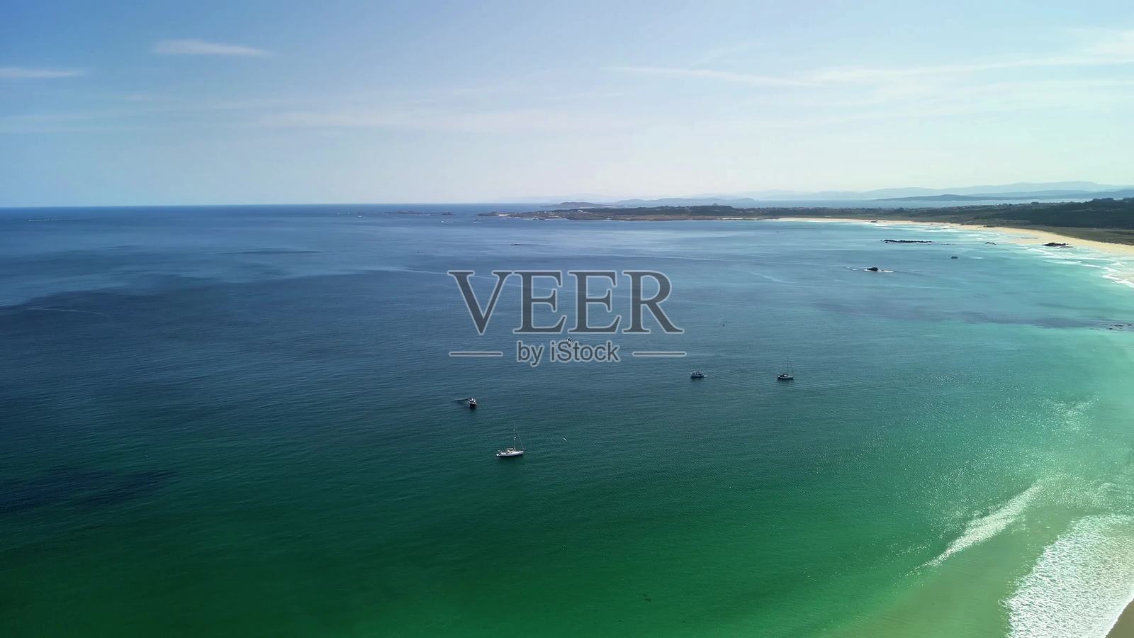 阳光明媚的日子，宁静海滩的鸟瞰图，四周环绕着清澈的海水照片摄影图片