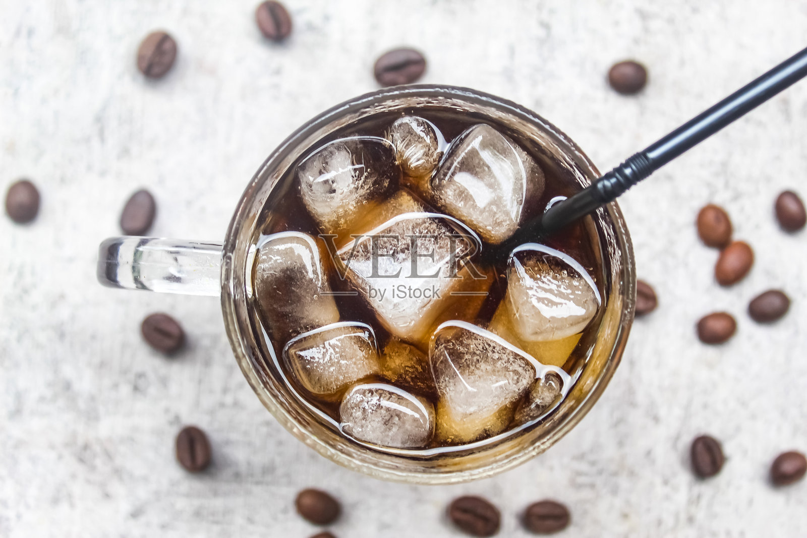 从上方俯视一杯冰咖啡，旁边有冰块和咖啡豆照片摄影图片