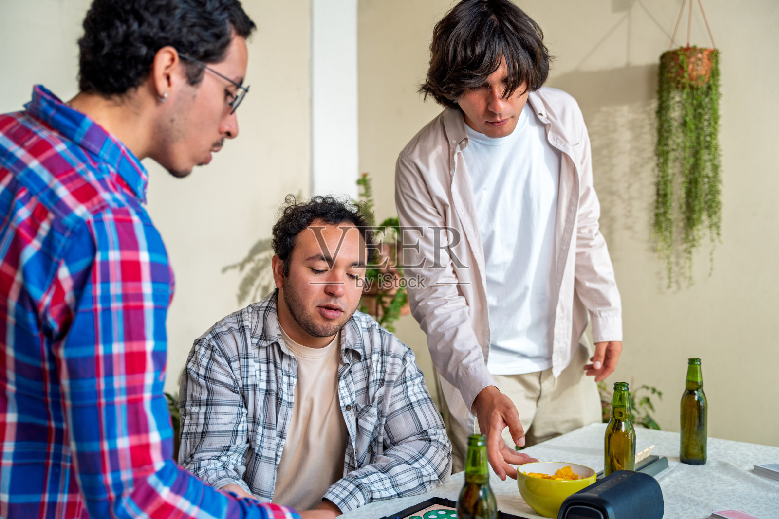 一群朋友在家里玩牌，喝啤酒，吃零食照片摄影图片