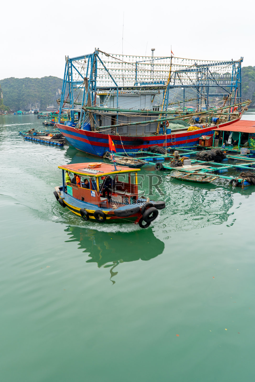 一只小船驶过越南的传统渔船，展示当地文化。照片摄影图片