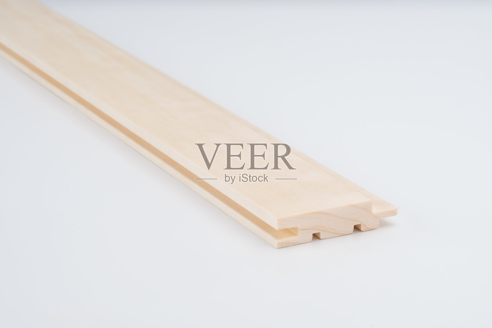 浅色木材轮廓，带有复杂的凹槽设计，拍摄于白色背景上。用于建筑或橱柜的精密切割组件。照片摄影图片