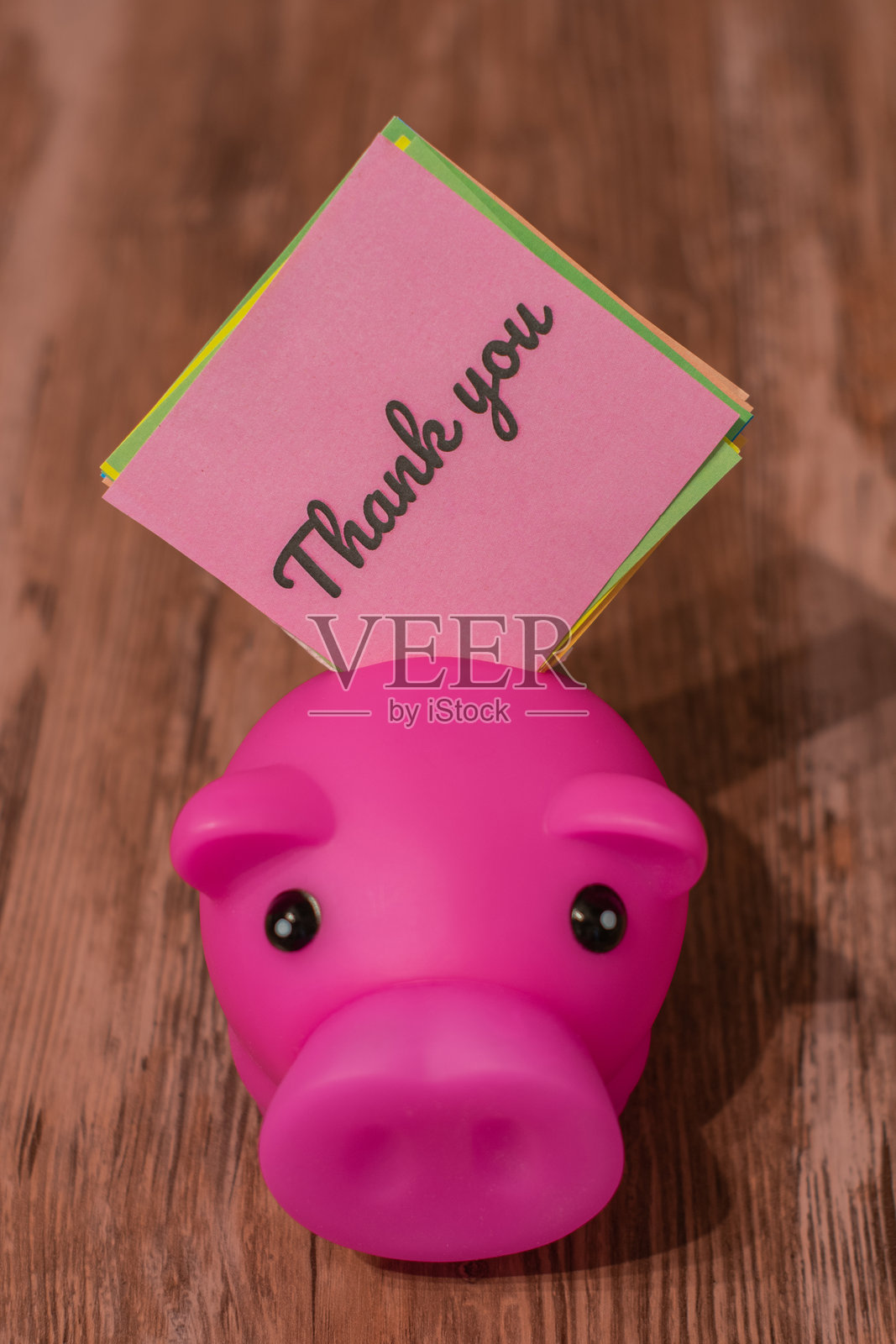 粉色感谢卡放在木质表面的储蓄罐里。照片摄影图片