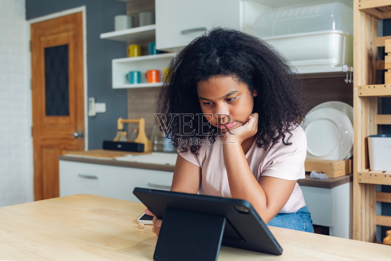 女孩在家中使用平板电脑，微笑着听音乐或玩游戏。女孩们在家中与平板电脑一起。照片摄影图片