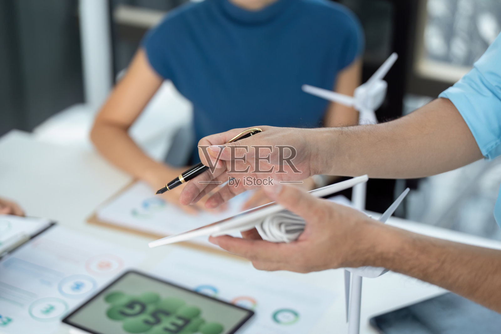 展示ESG策略。专业人士手持风力涡轮机模型，讲解可持续发展概念。照片摄影图片