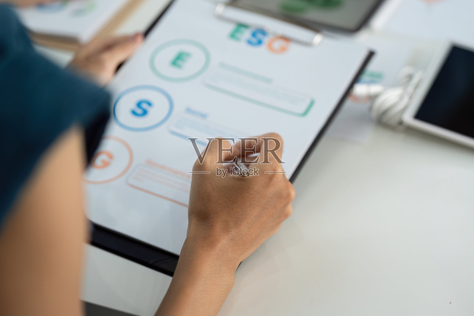 ESG焦点。个人在夹板上分析环境、社会和治理指标。照片摄影图片