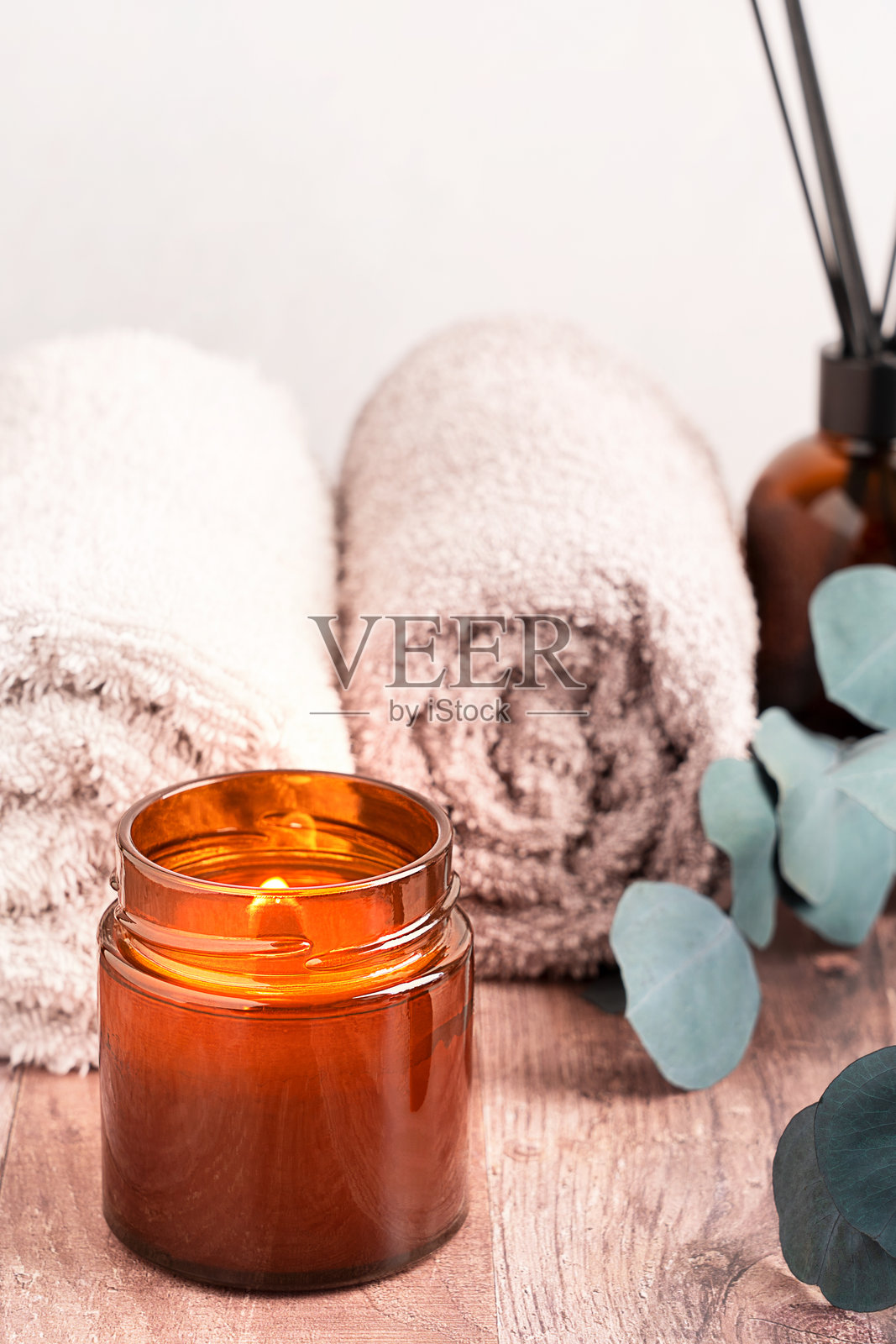 放松的水疗场景，浴室木桌上摆放着散发香气的发光蜡烛和卷好的毛巾照片摄影图片