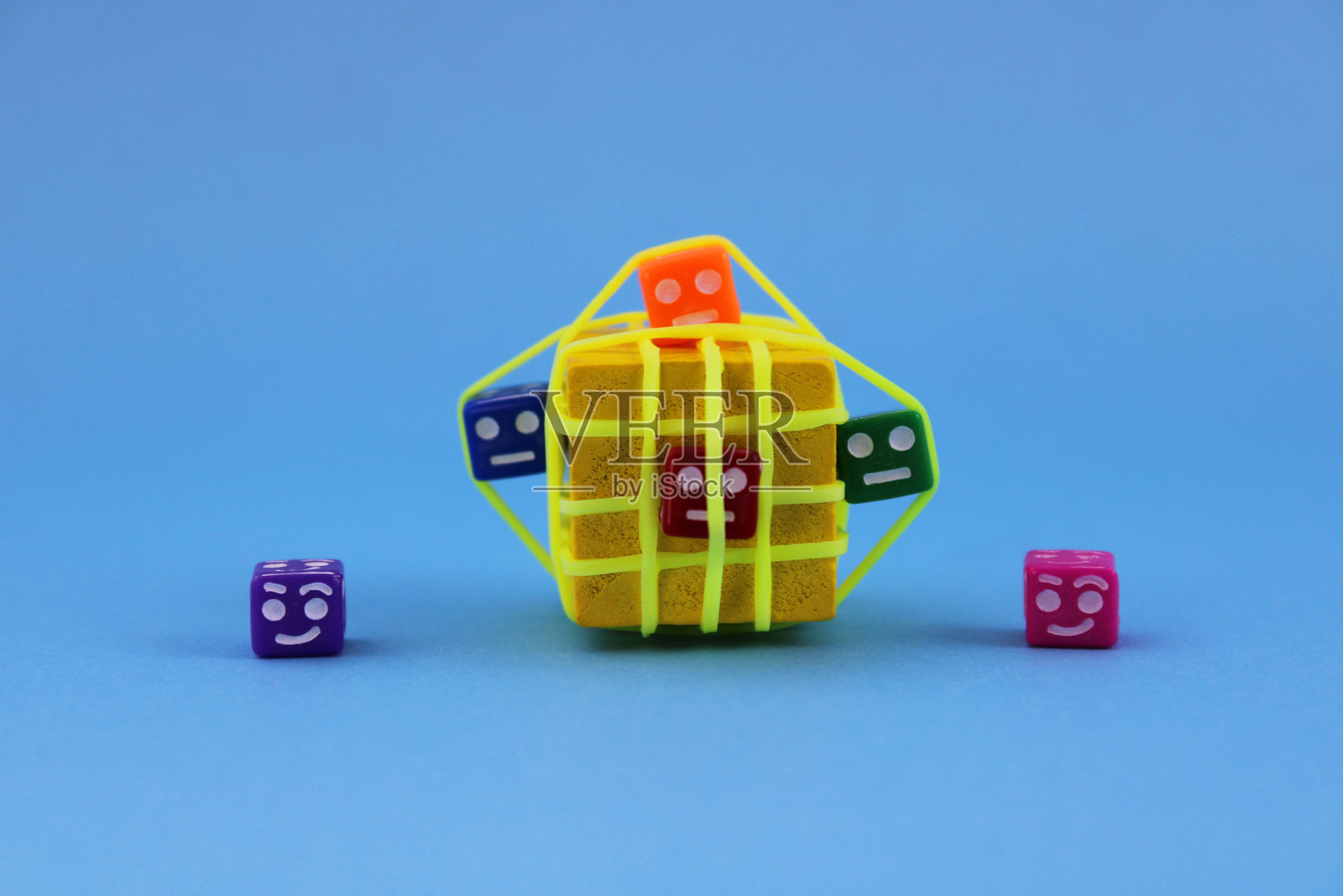 被橡皮筋困住的带有悲伤面孔的彩色立方体，旁边是自由的带有快乐面孔的其他立方体照片摄影图片