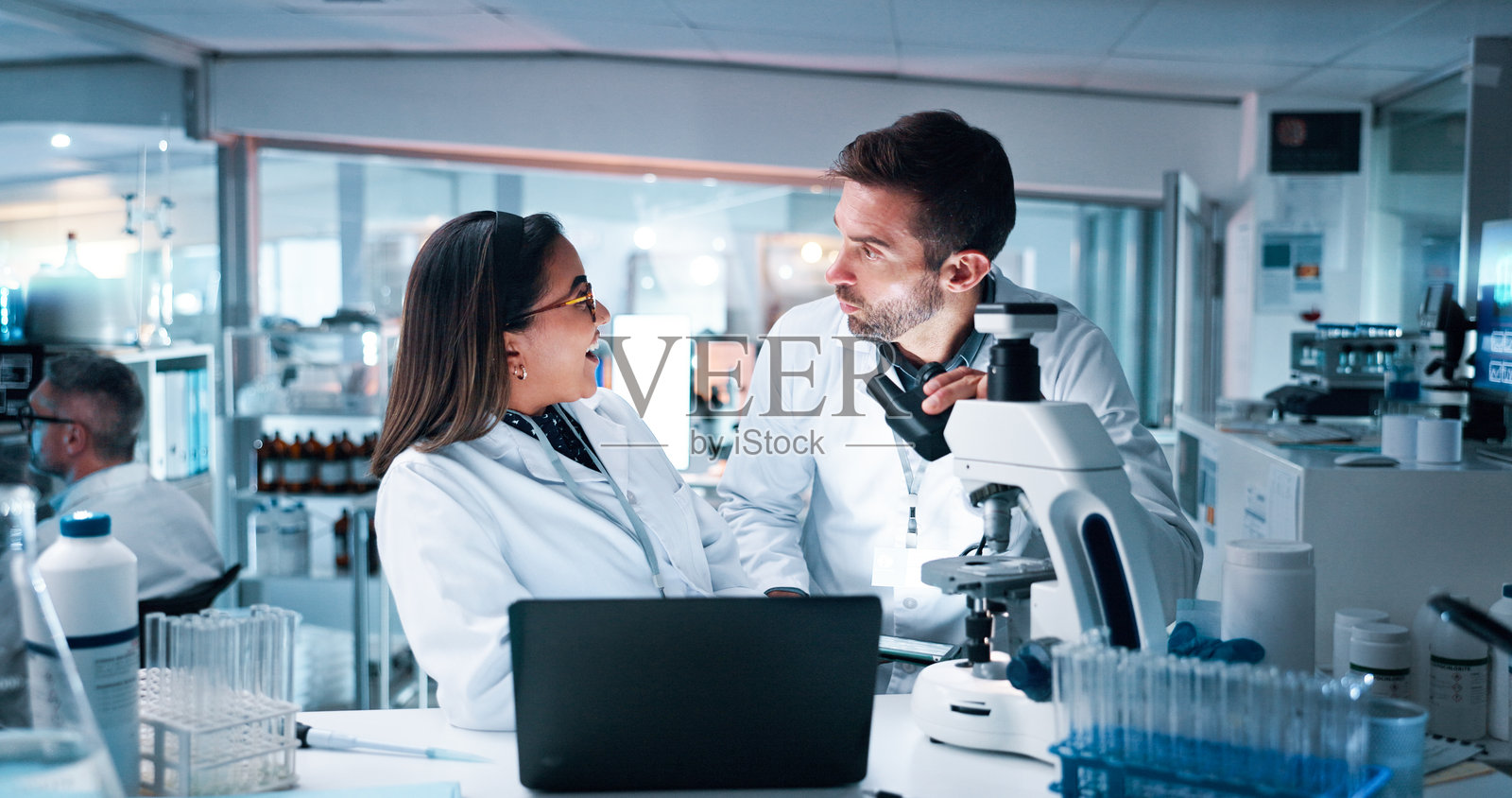实验室里的人们一起进行开发，使用笔记本电脑、显微镜和科学设备。医疗团队在临床试验中进行对意外突破反应的讨论与合作。照片摄影图片