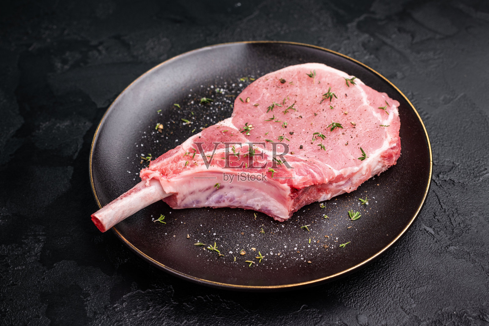 多汁的带骨生猪排，等待被转变为您餐桌上的美味中心菜肴。黑色背景。俯视图。照片摄影图片