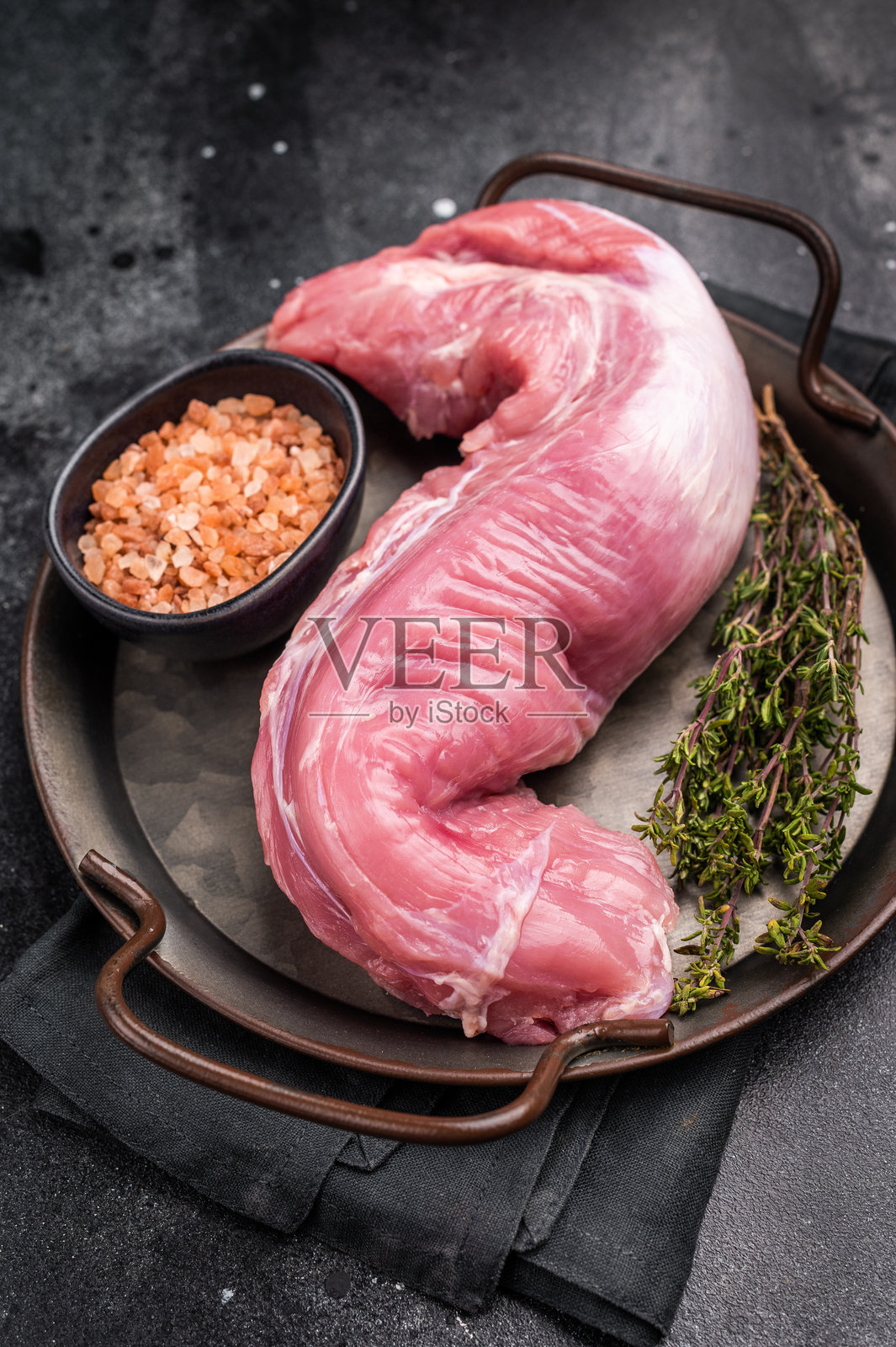 新鲜的猪里脊肉，展示其瘦肉切割，适合腌制和烤制至多汁完美。黑色背景。俯视图。照片摄影图片