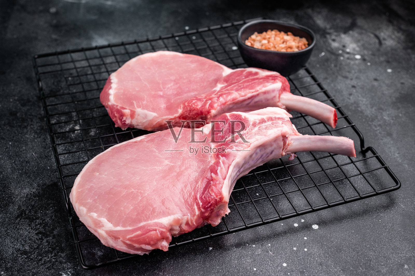 新鲜的猪排托马霍克牛排，展示了其令人印象深刻的骨头和大理石纹理的肉，适合烧烤或烘烤。黑色背景。俯视图。照片摄影图片