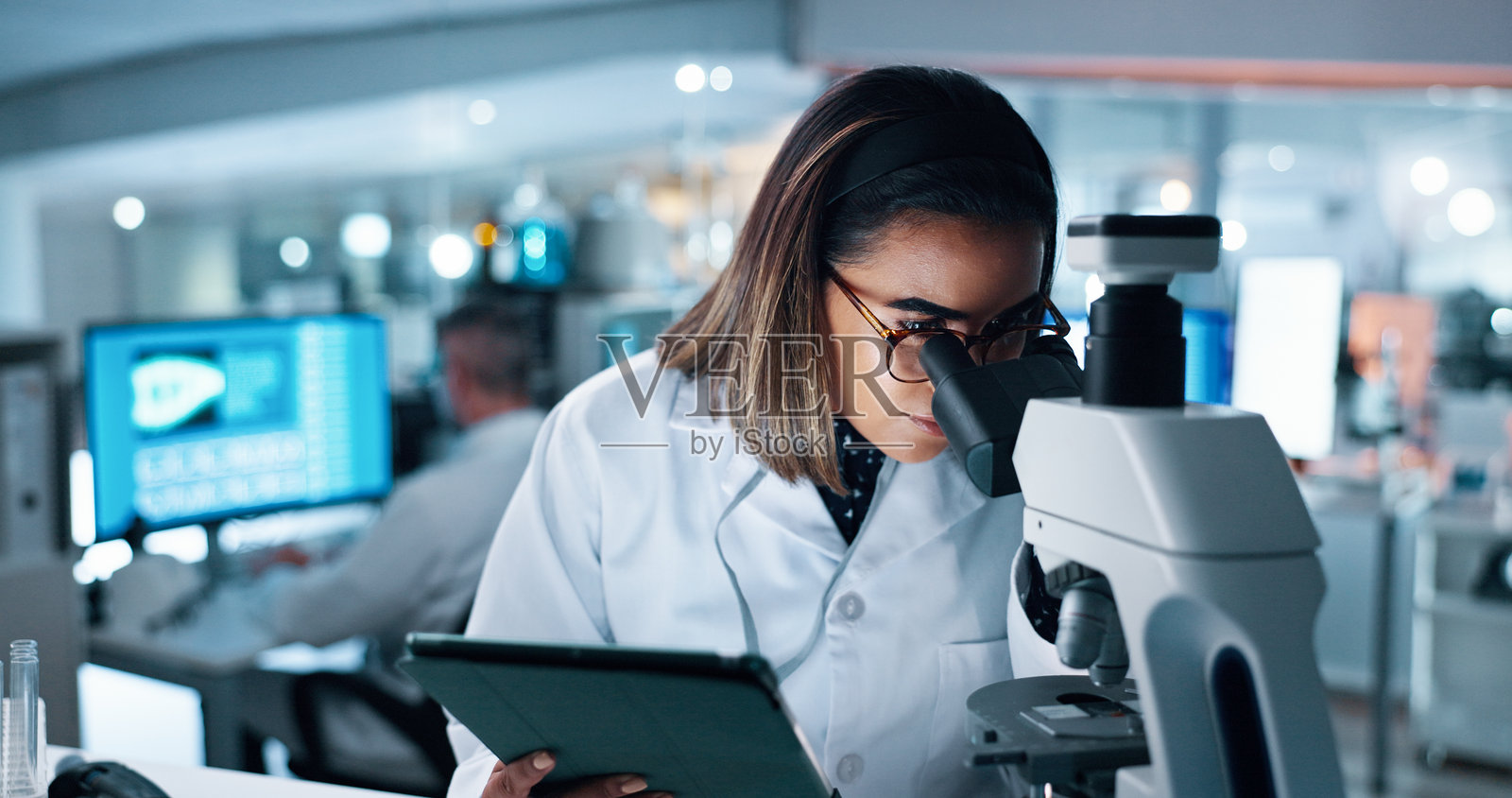 实验室中的女性科学家使用显微镜进行医学研究和DNA分析。实验、调查以及男性生物学家在生物技术领域进行制药临床试验。照片摄影图片