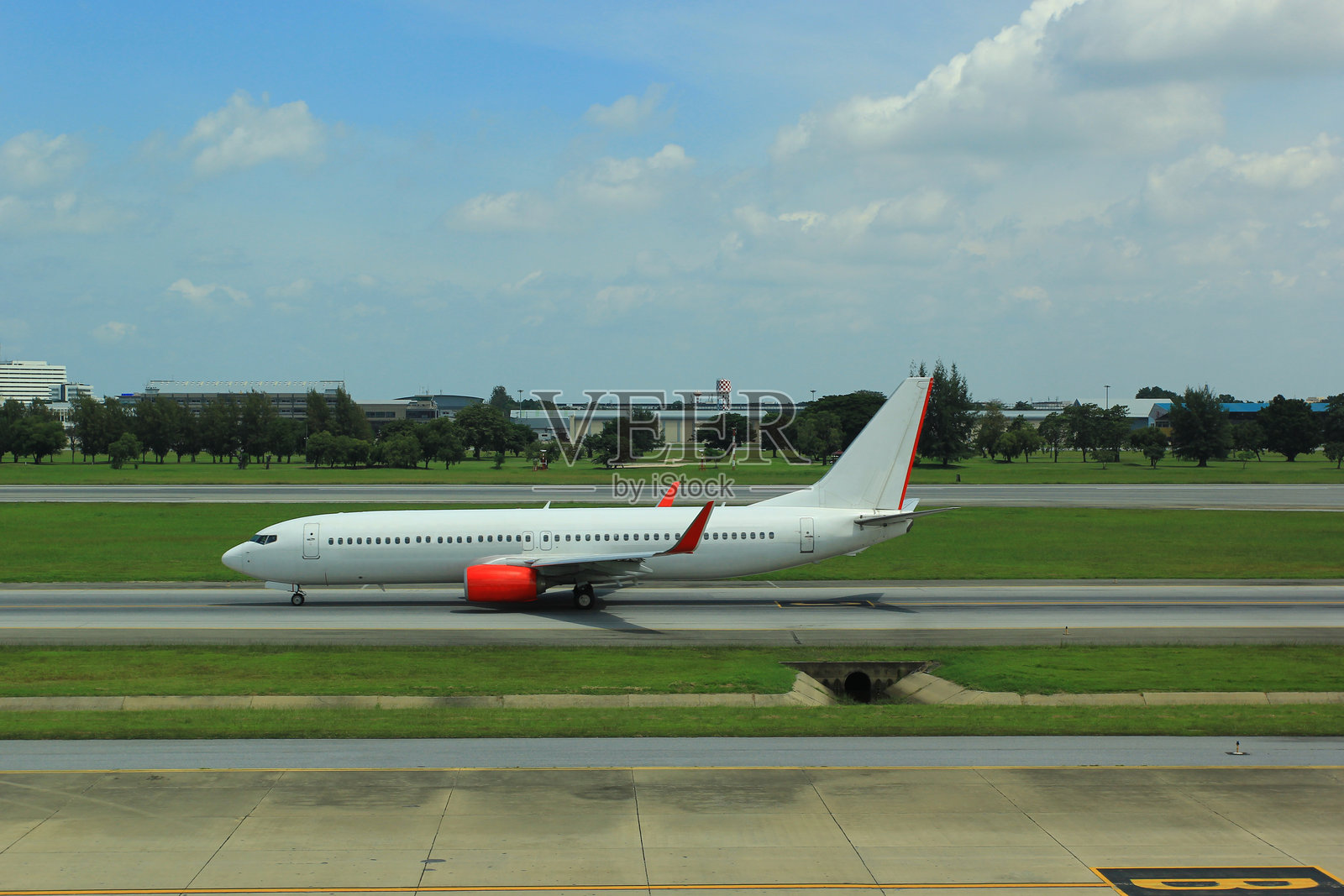 宽角度视图的白色客机在阳光明媚的机场滑行道上行驶。旅行与交通概念。照片摄影图片