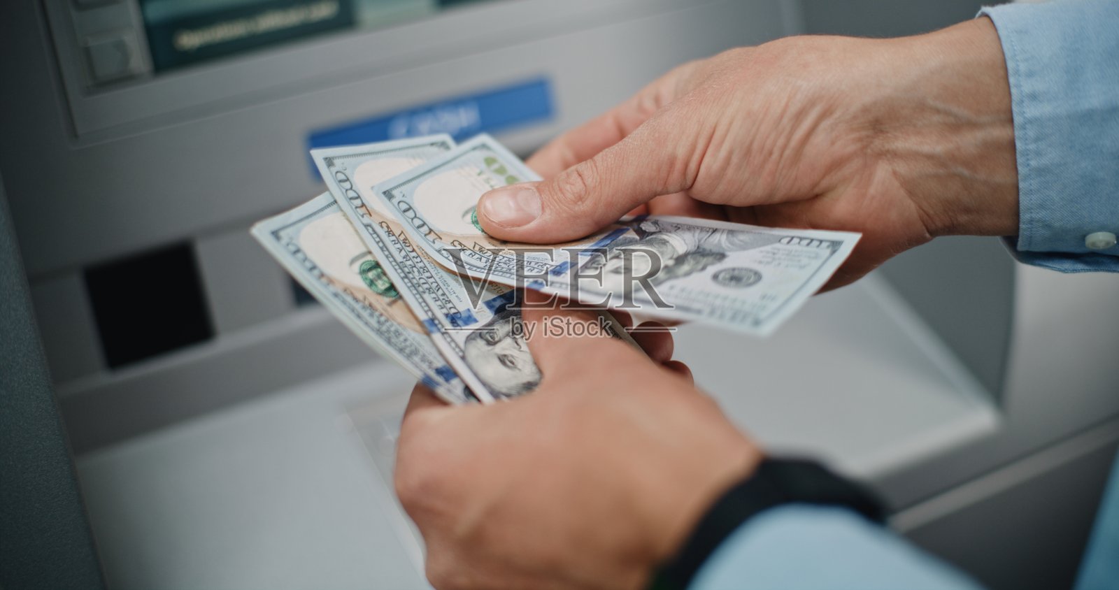 特写镜头：一个无法辨认的男子在取款后数美金钞票照片摄影图片