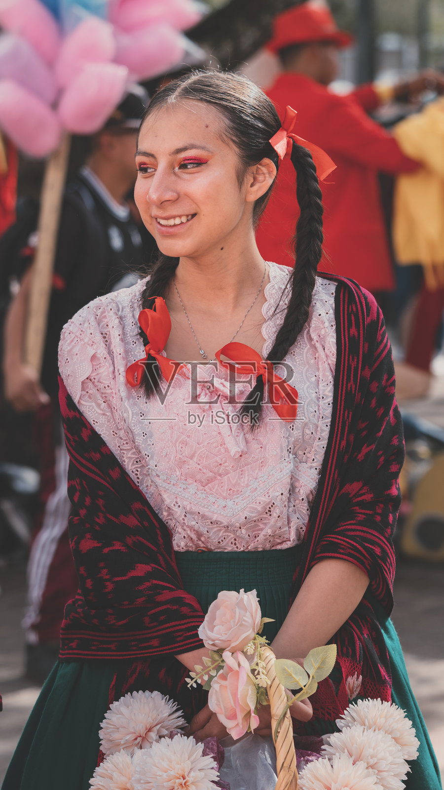 身穿传统安第斯服饰的年轻女性手持花篮，参加库恩卡的狂欢节游行照片摄影图片