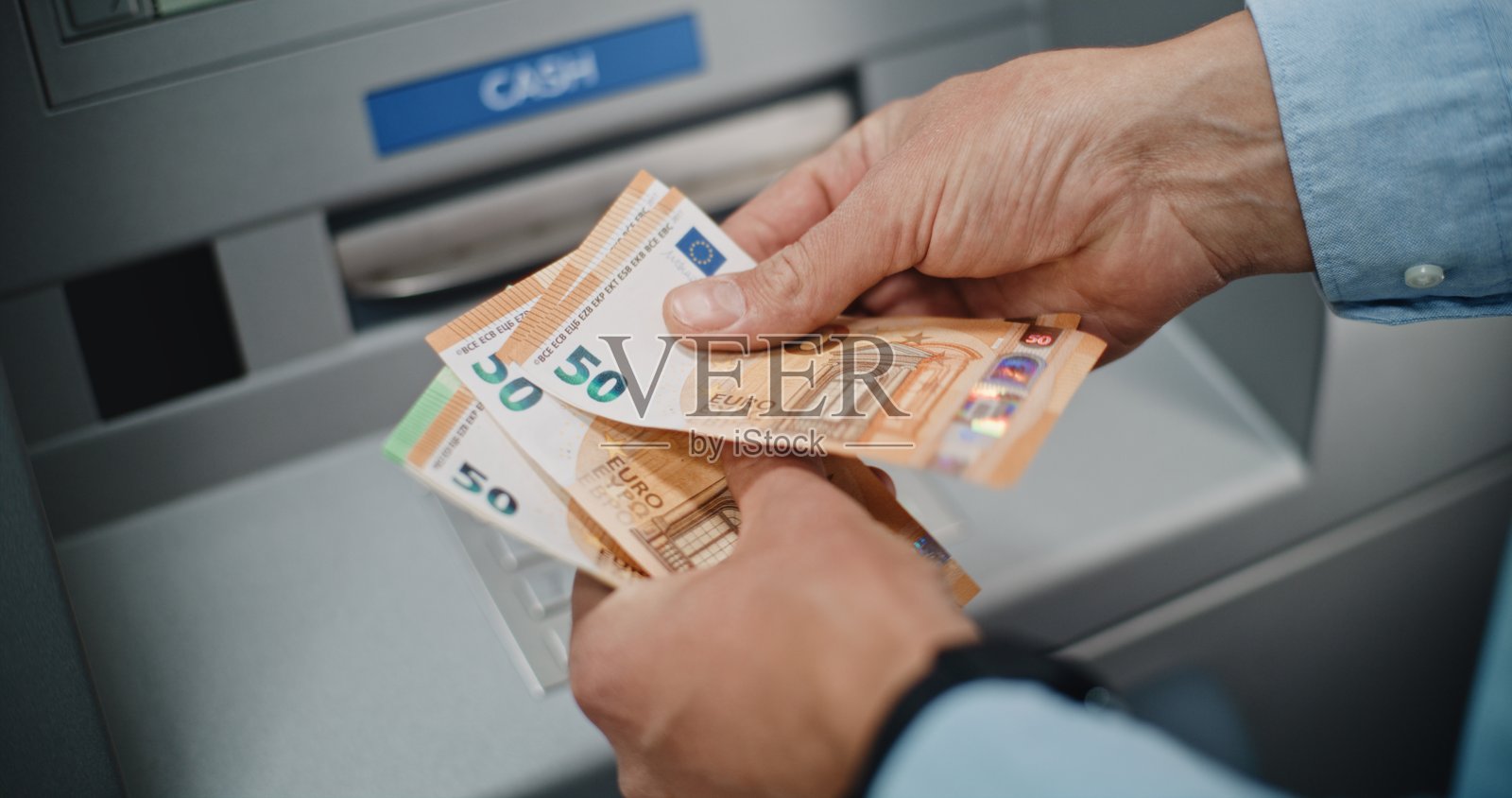 特写镜头：一个无法辨认的男子在取款后数欧元钞票照片摄影图片