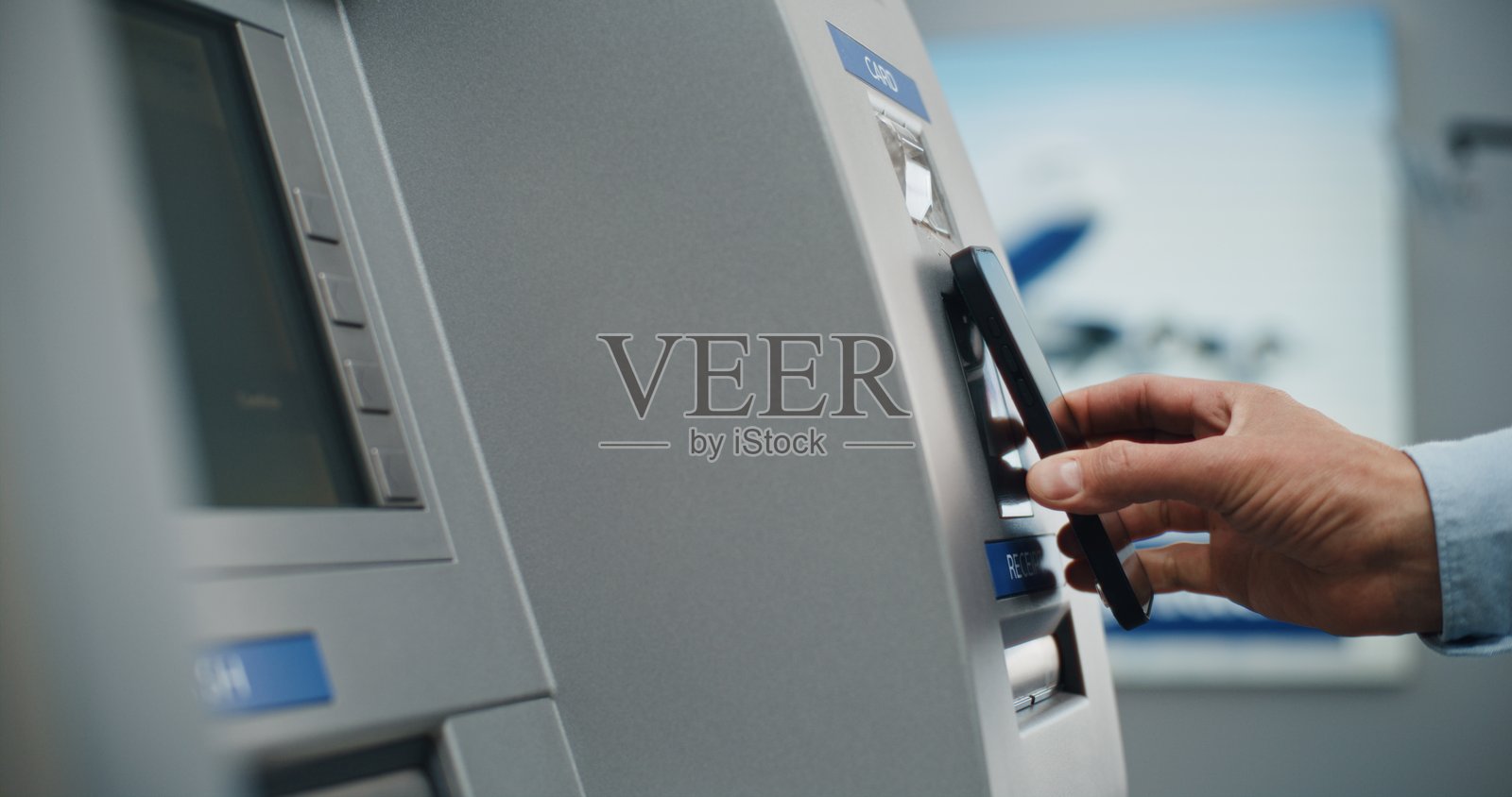 ATM机：特写镜头显示一个人将智能手机靠近NFC读卡器进行无接触取款照片摄影图片