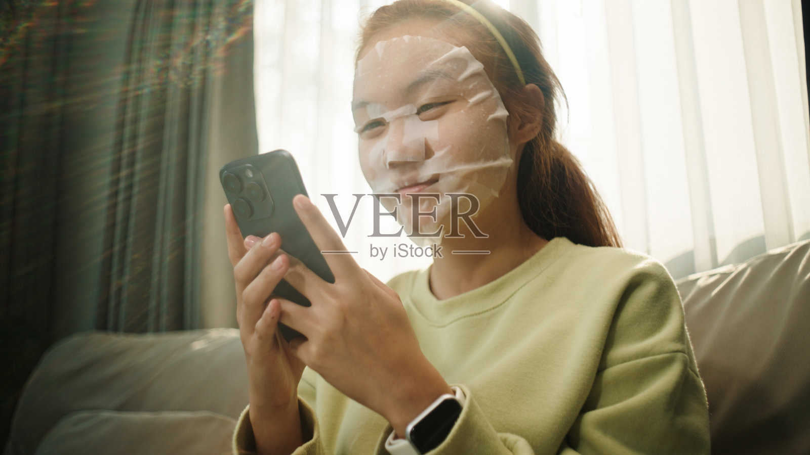 戴着面膜的青少年使用智能手机。照片摄影图片