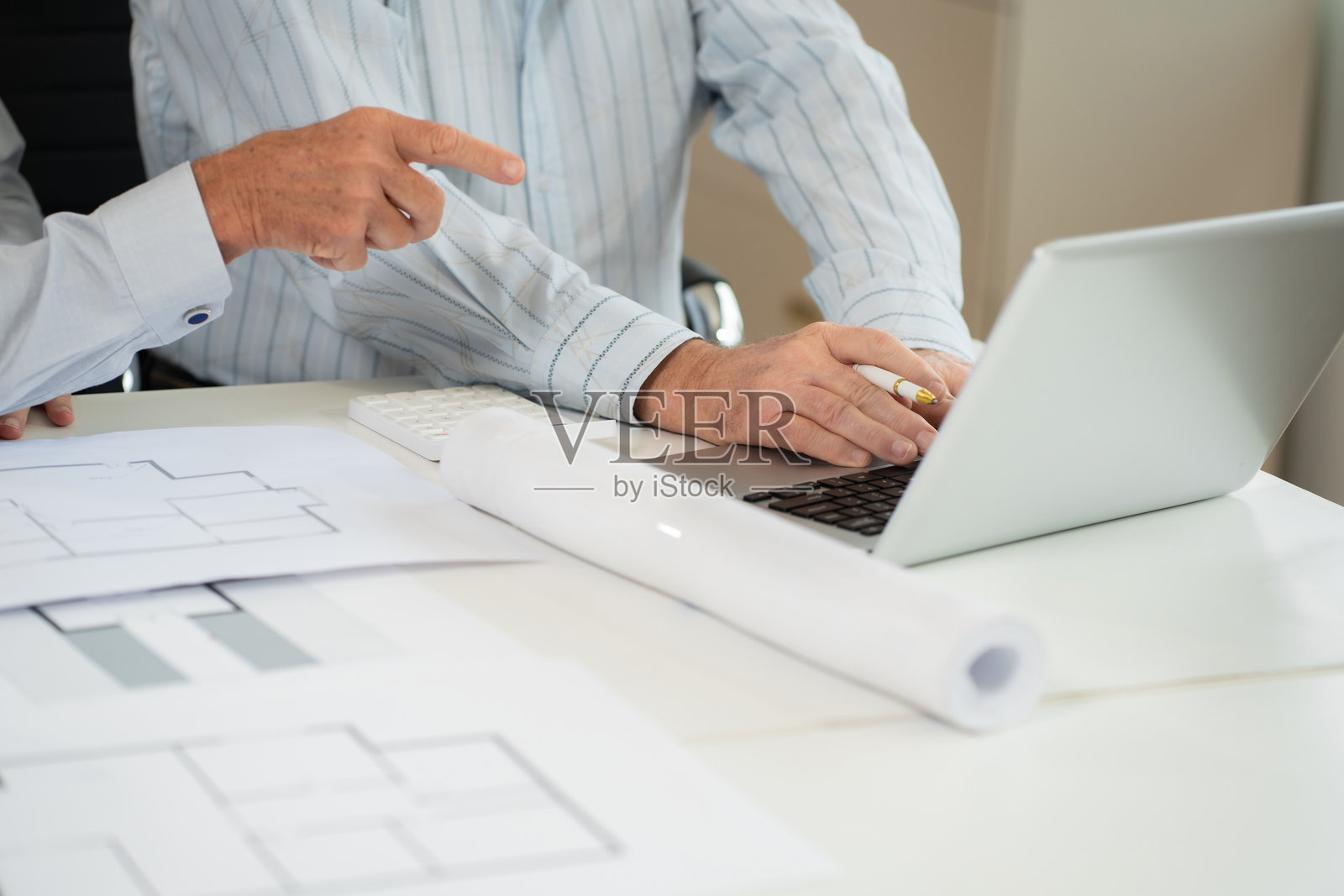 白人建筑师在桌子上使用绘图工具绘制商业建筑项目的纸质计划。照片摄影图片