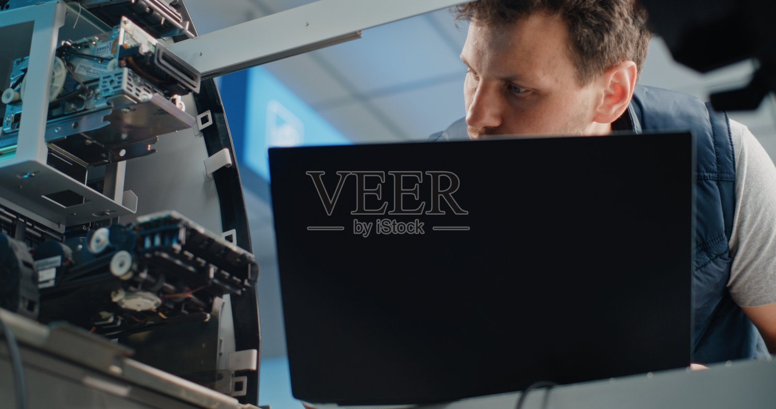 穿着制服的技术人员使用笔记本电脑，调整自动取款机内部组件照片摄影图片