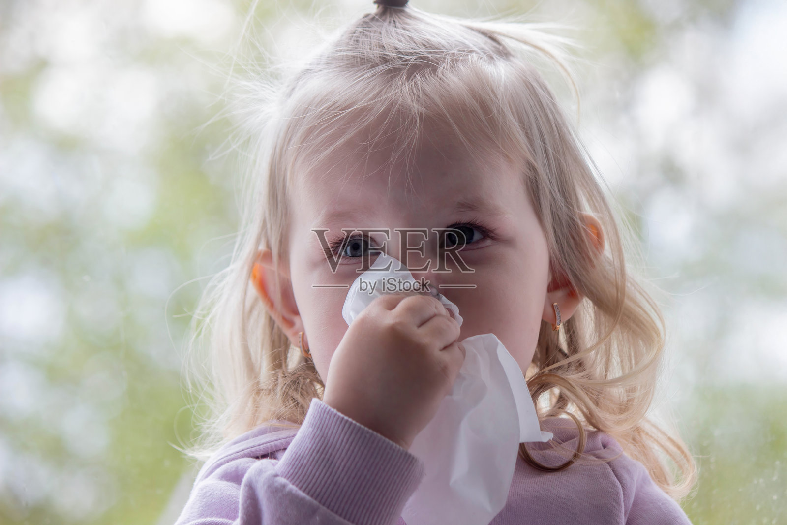 小孩用纸巾擦鼻涕，感冒了。选择性聚焦。照片摄影图片